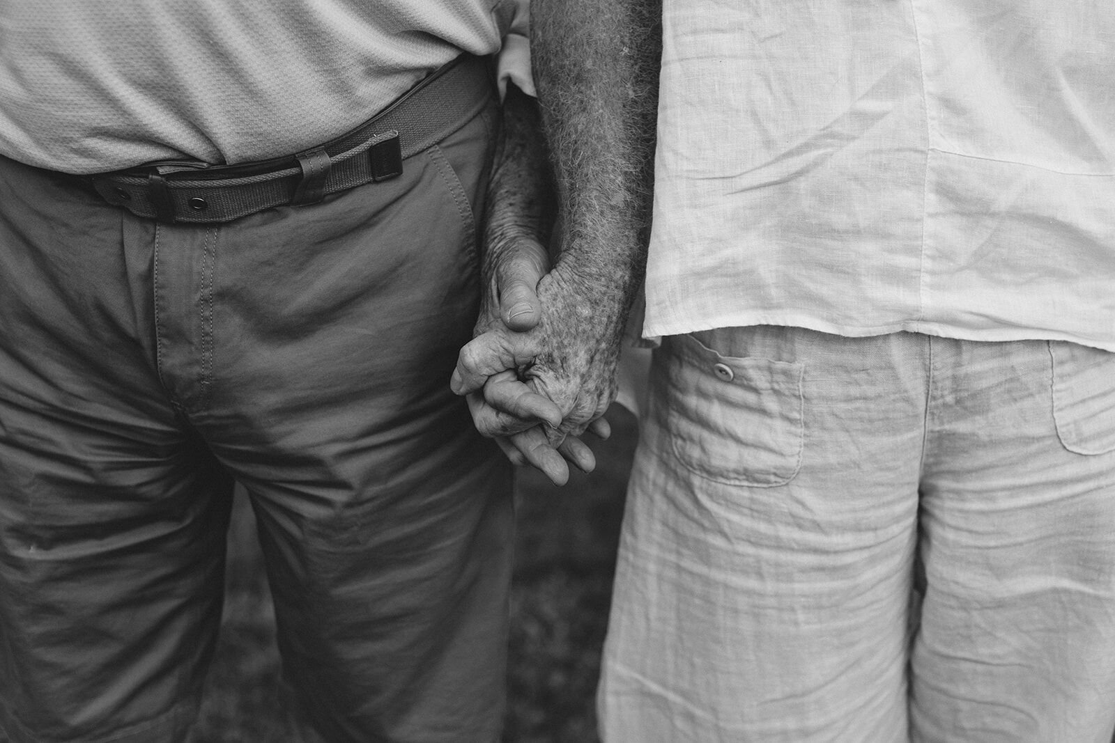 Black and white detail of a grandfather and grandmother holding hands