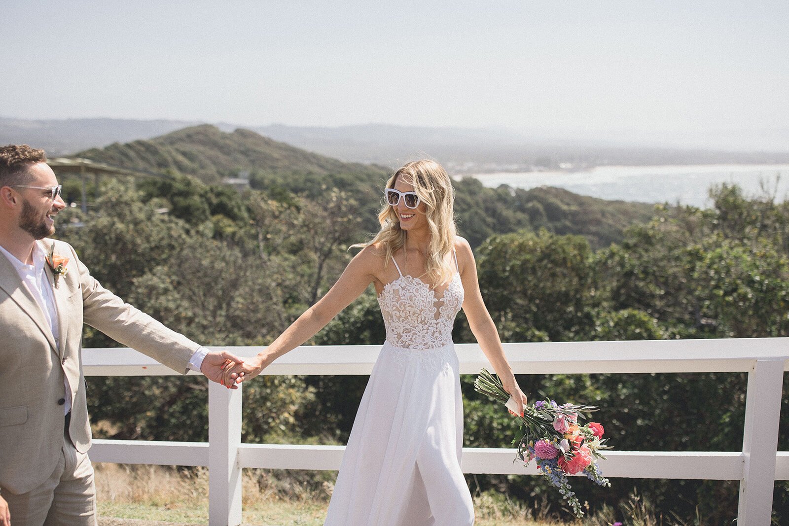 Couple holding hands at a lookout above the coastline, Eliza and Greg's elopement at Broken Head, Byron Bay