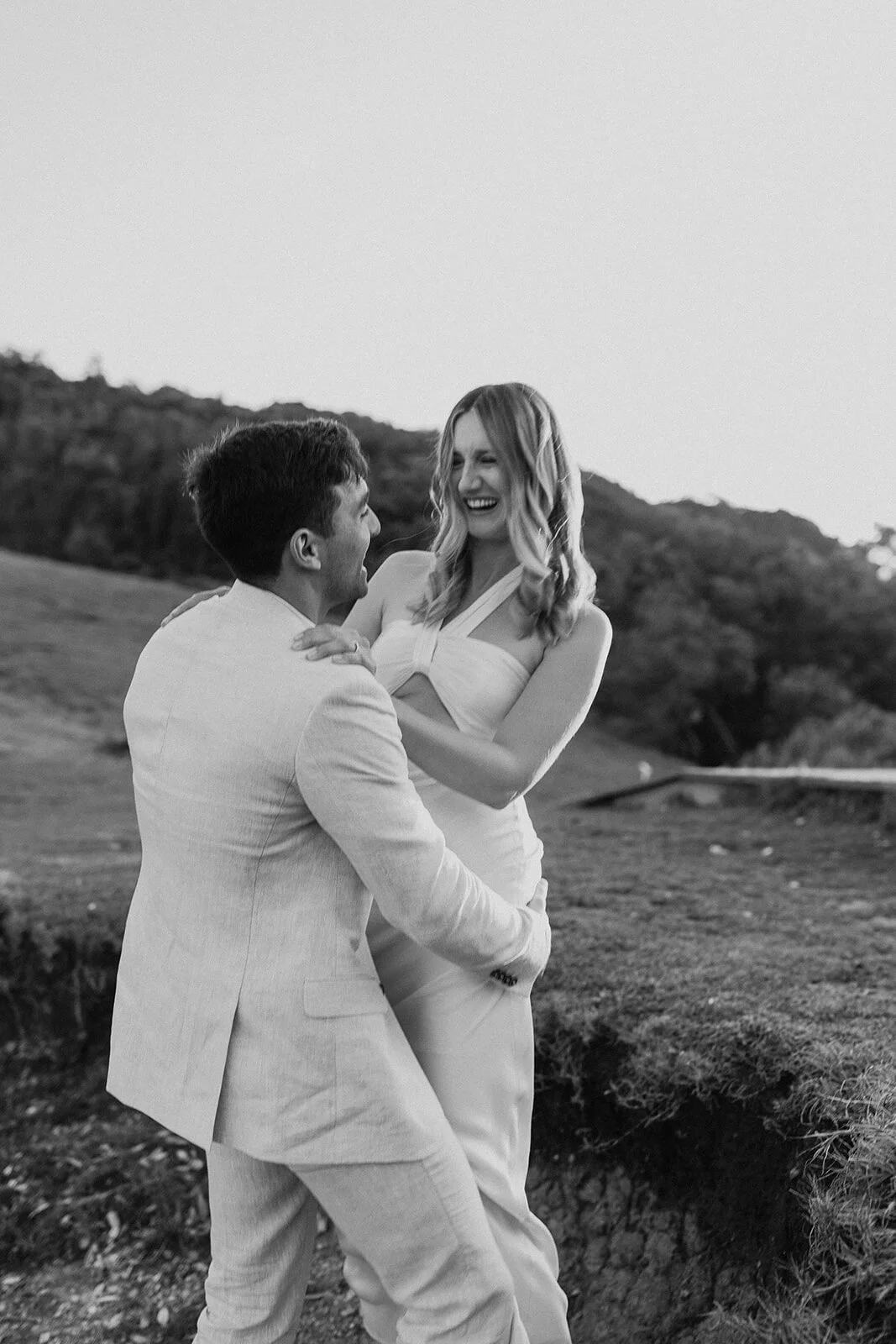 Black and white of the groom holding the bride on the headland, Abby and James' elopement at Little Wategos Beach, Byron Bay