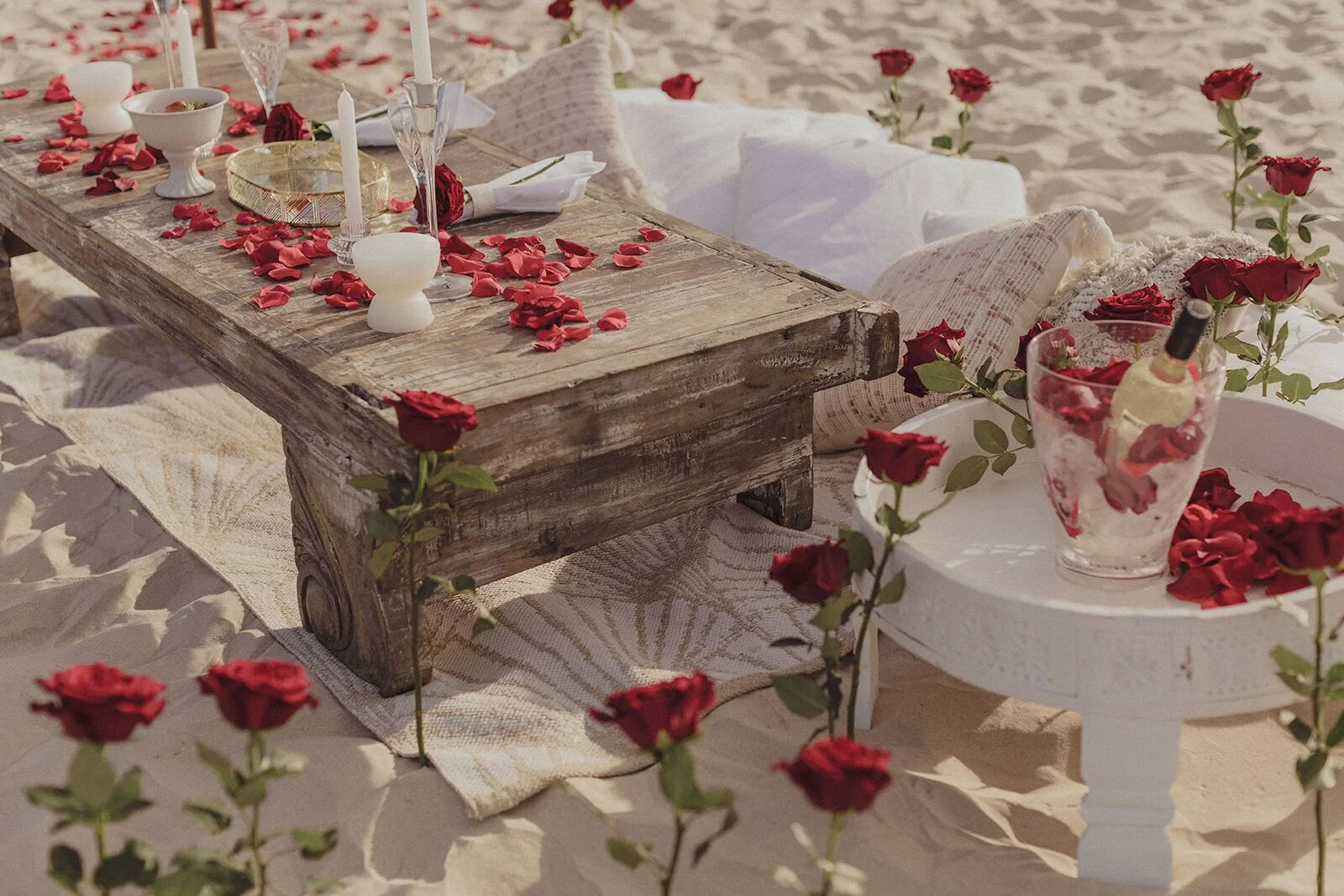 Rustic timber table with red rose petals and champagne set up on the beach, Byron and Luke's marriage proposal at Cabarita Beach, Northern Rivers