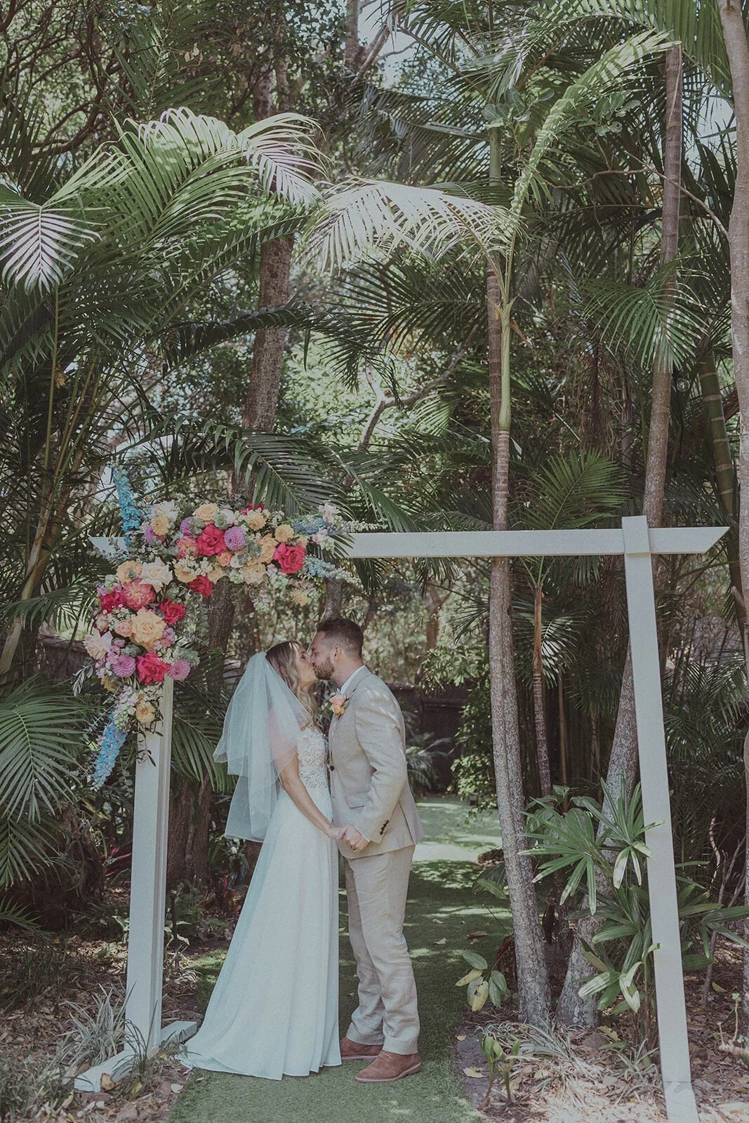 Couple kissing under the floral arch, Eliza and Greg's elopement at Broken Head, Byron Bay