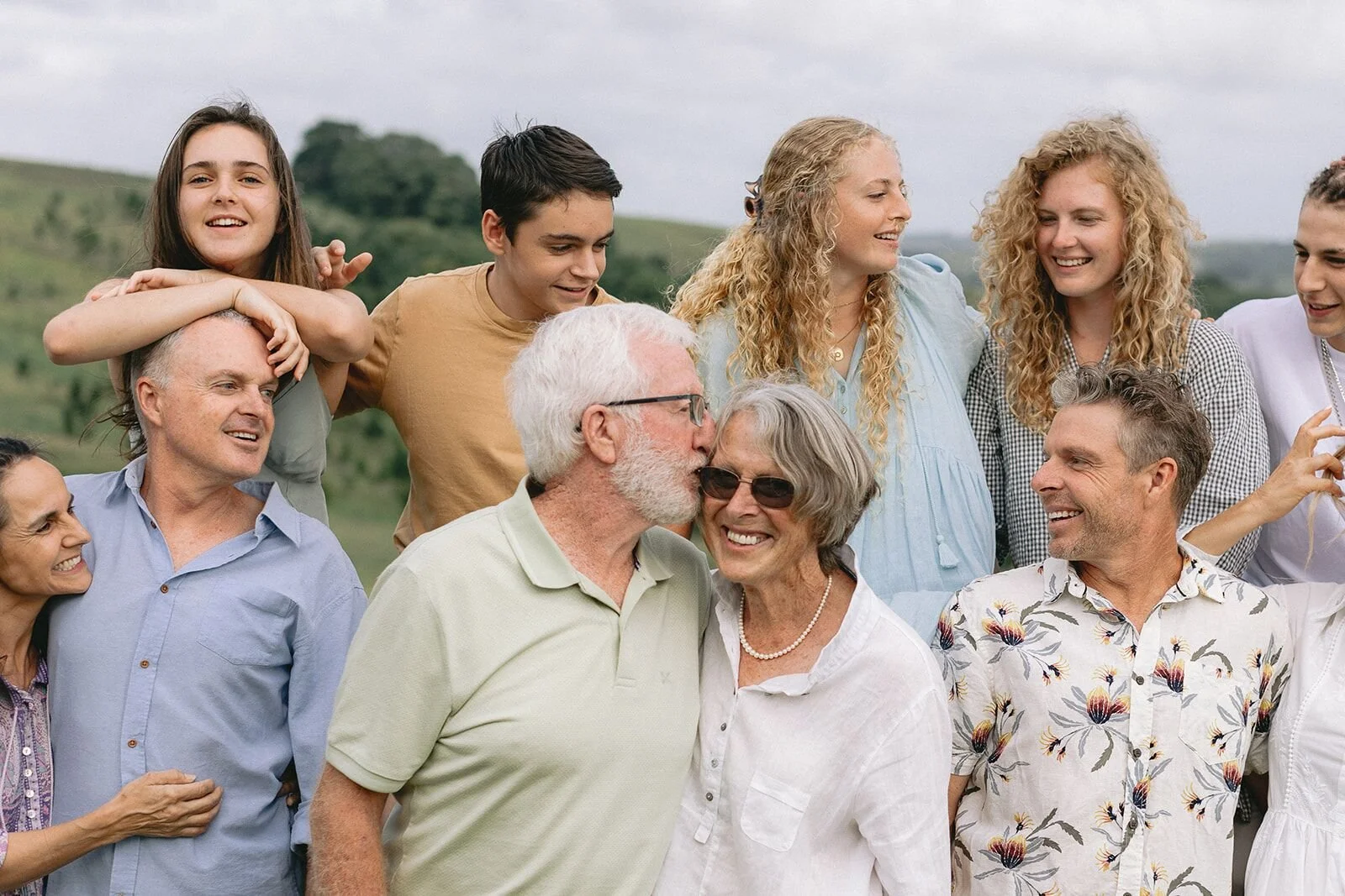Close-up of a multigenerational family laughing together, grandfather kissing grandmother on the cheek