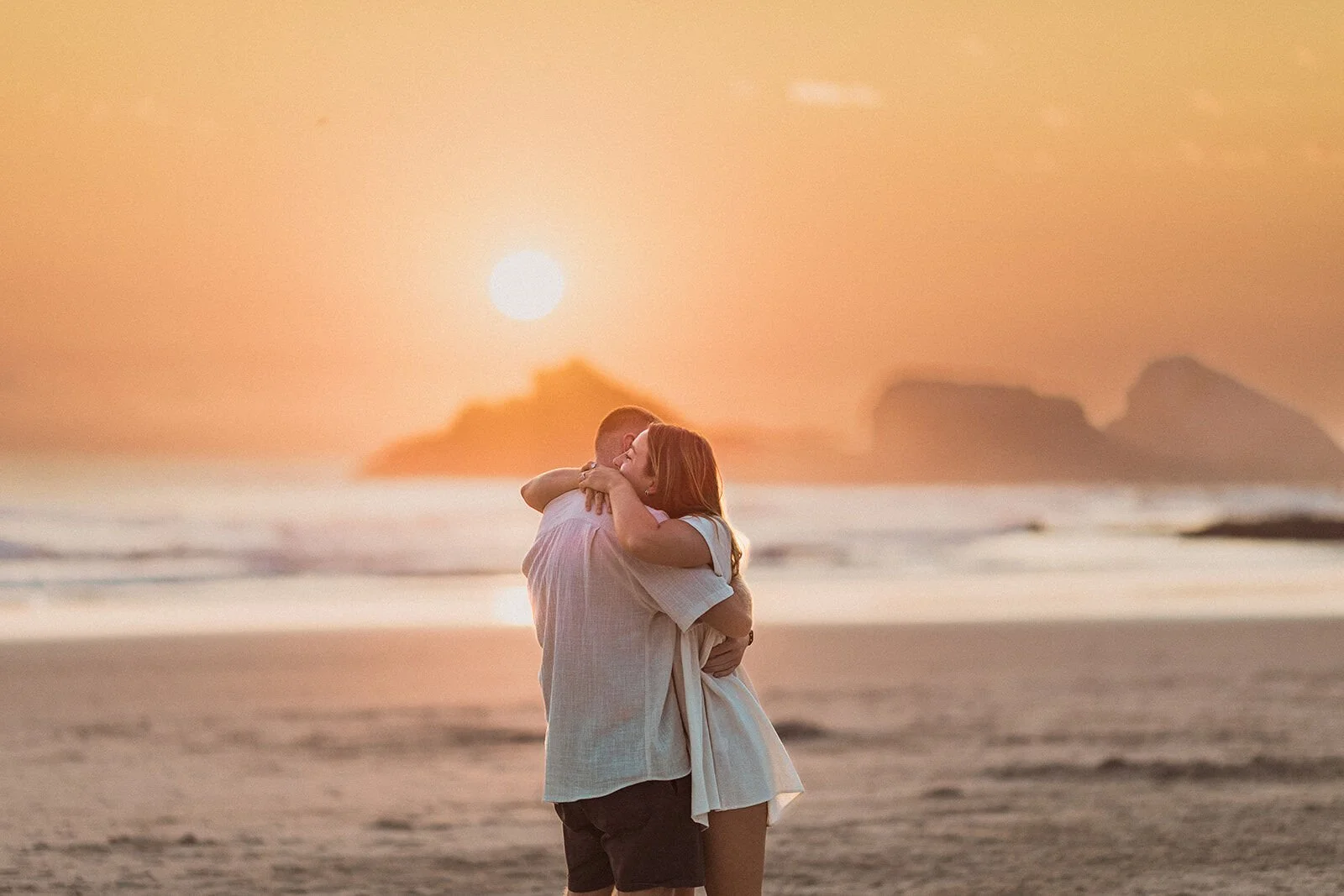 Couple embracing at sunrise with the sea stacks behind, Charlie and Hannah's sunrise marriage proposal at Broken Head Beach, Byron Bay
