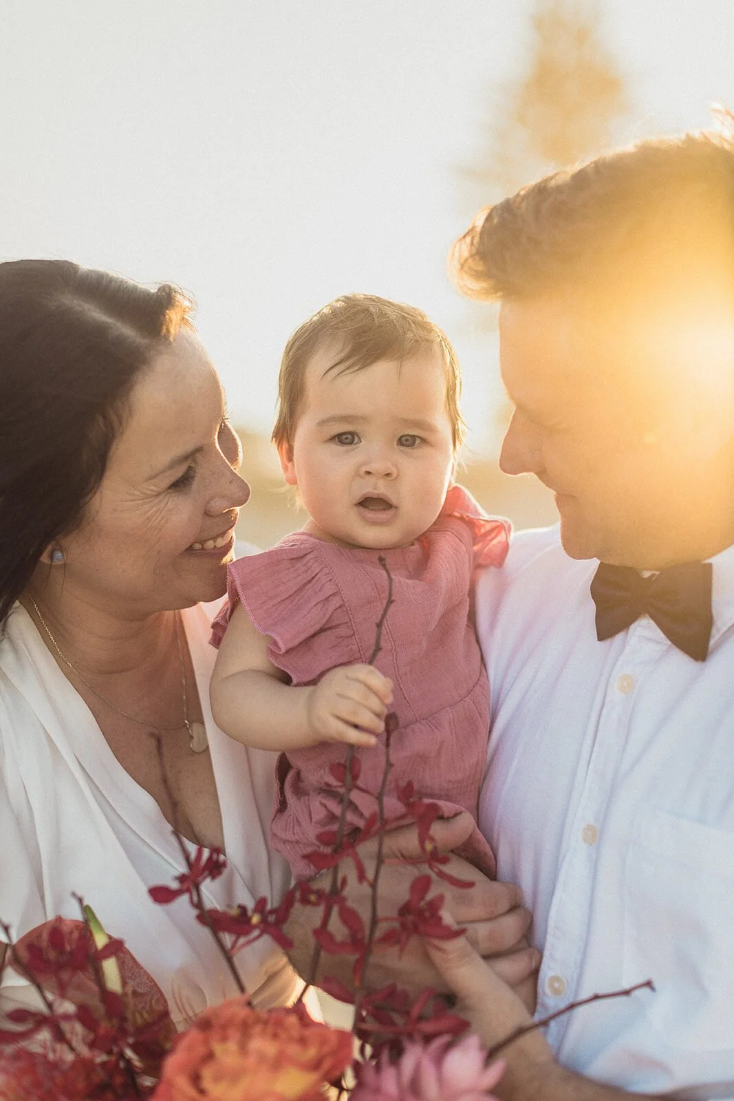 Bride and groom holding their baby in golden light, Maritess and Mark's elopement at Lennox Head