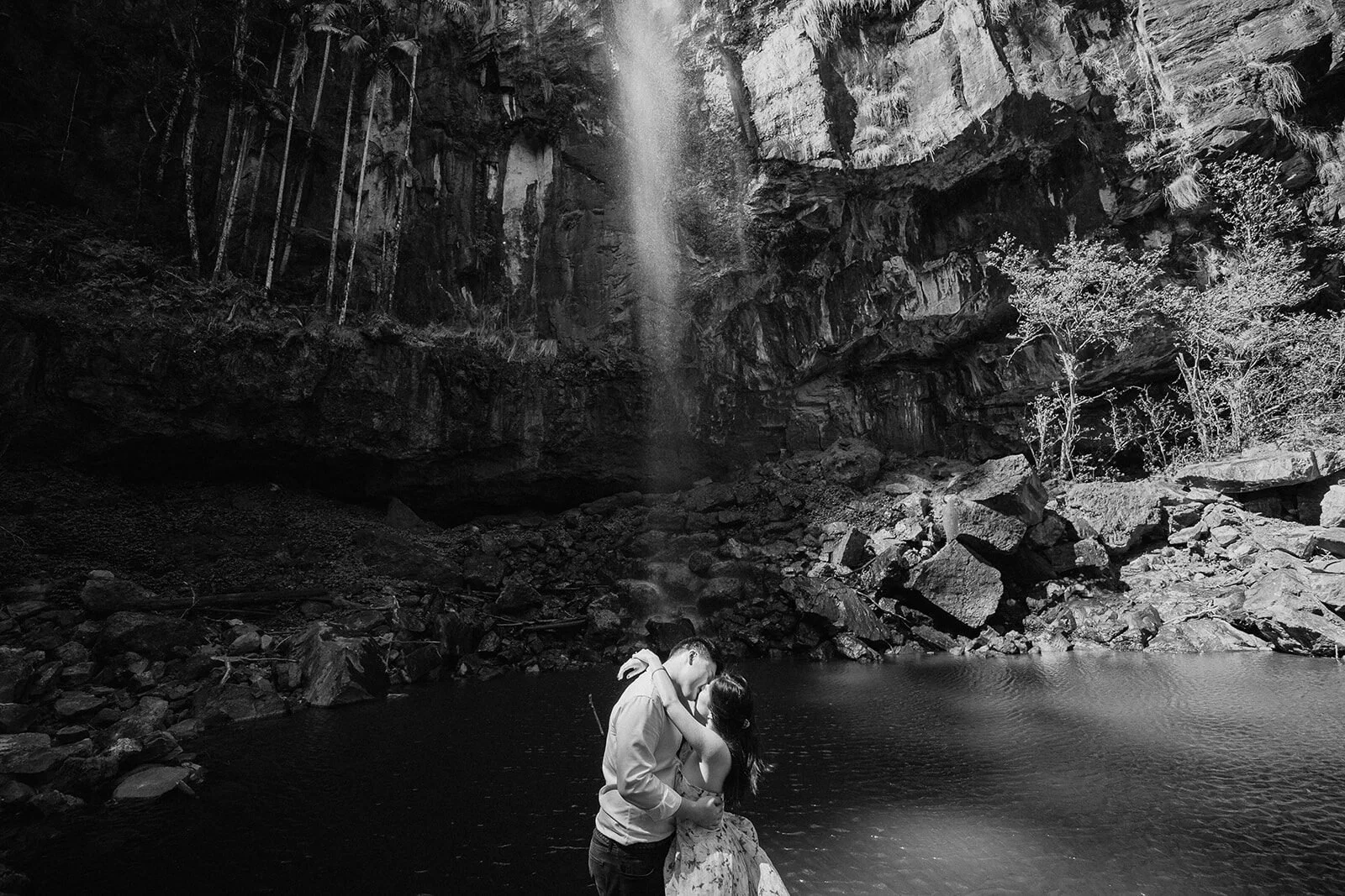 Black and white of the couple embracing at the waterfall pool, Maggie and William's pre-wedding photos in Byron Bay