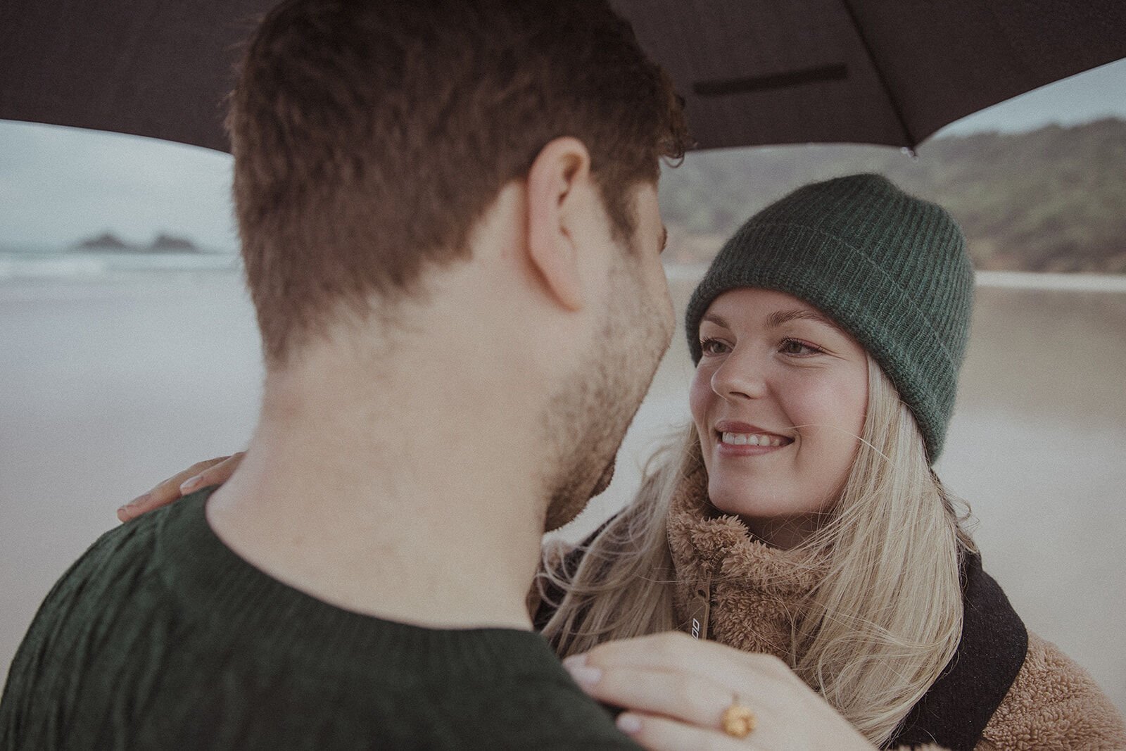 Close up of the woman smiling at her fiancé with her ring on his shoulder, Raphael and Vany's rainy day marriage proposal at Broken Head Beach, Byron Bay