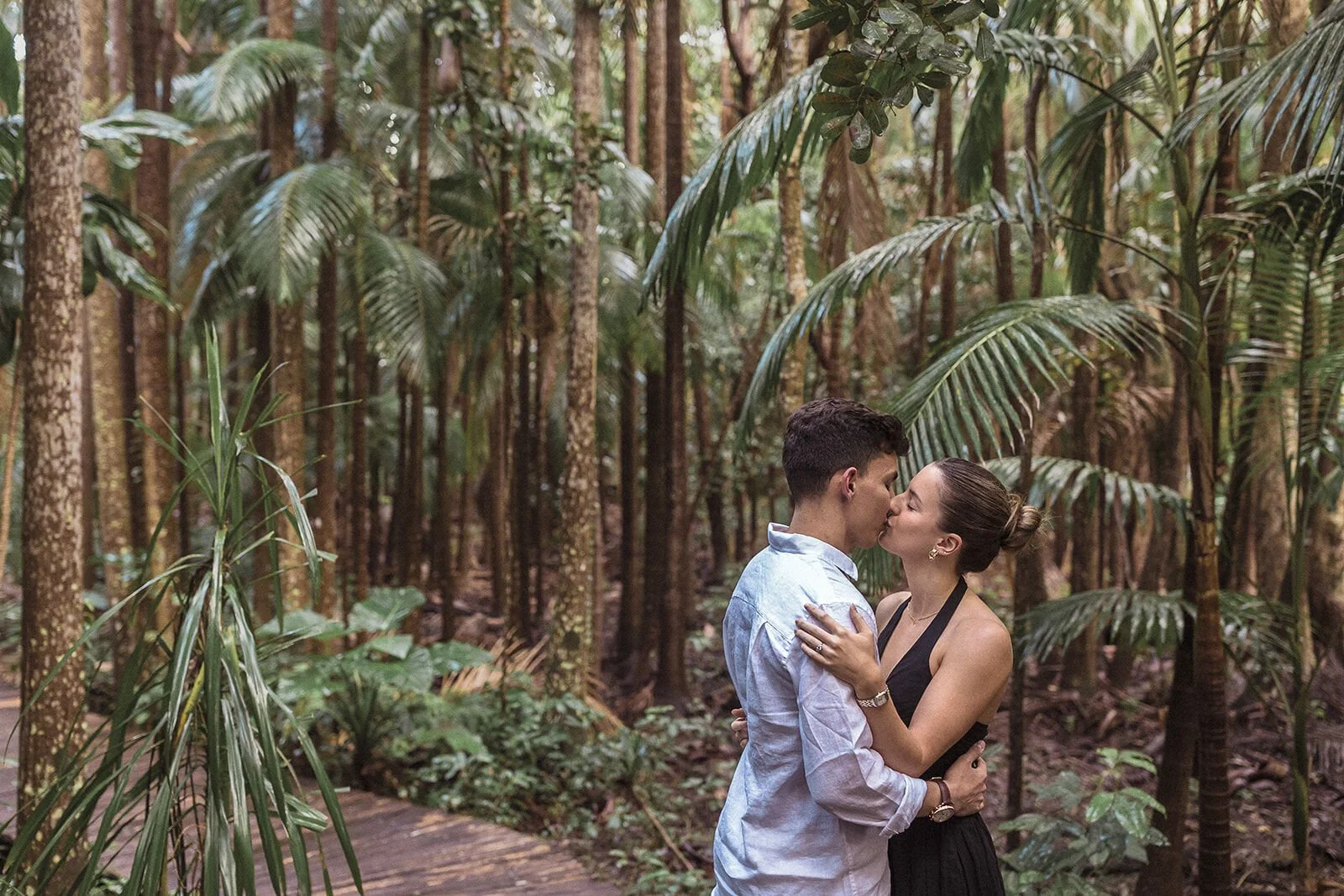 Couple kissing among tall palms in the rainforest, Ben and Chloe's marriage proposal in Byron Bay