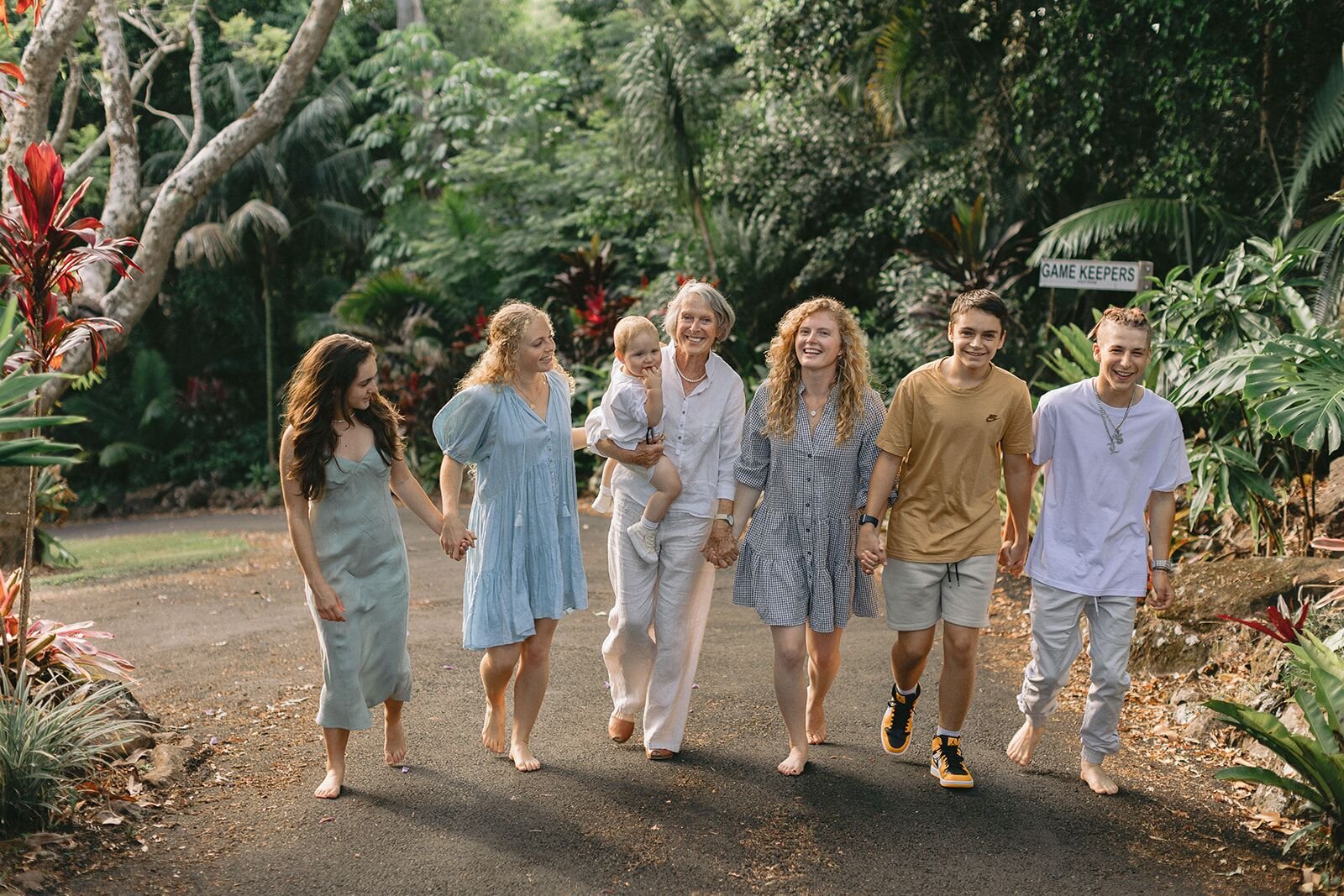 Three generations walking hand in hand along a tropical garden driveway at Possum Creek