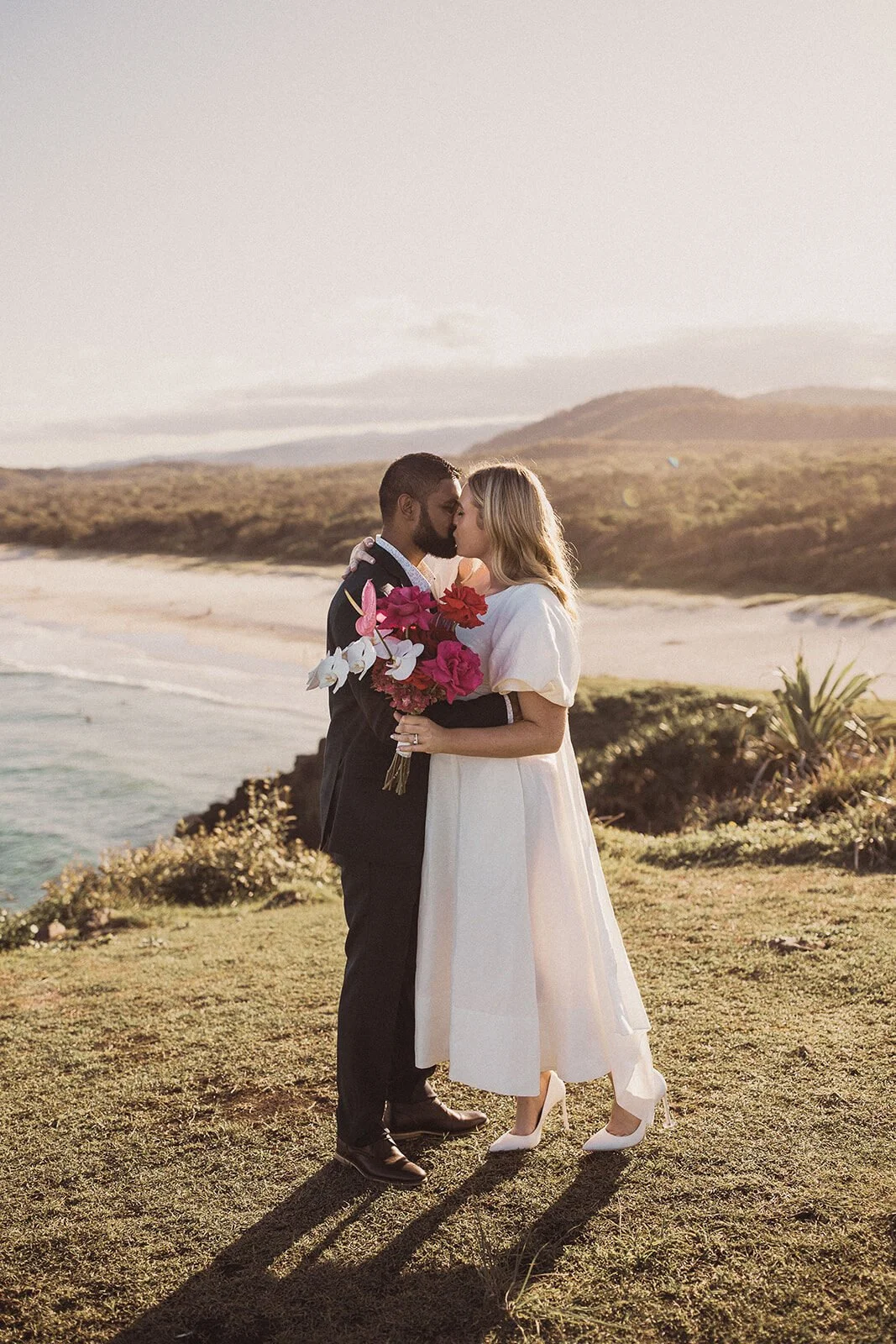 Couple kissing on the grassy headland, Brittany and Mark's elopement at Cabarita Beach, Northern Rivers