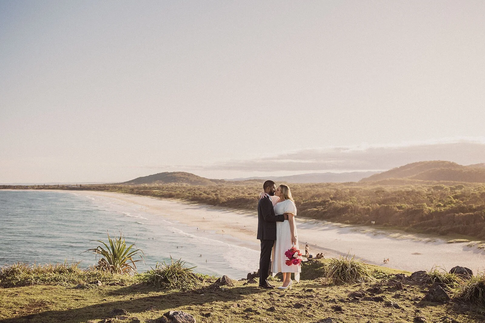 Couple embracing with the coastline stretching out behind, Brittany and Mark's elopement at Cabarita Beach, Northern Rivers