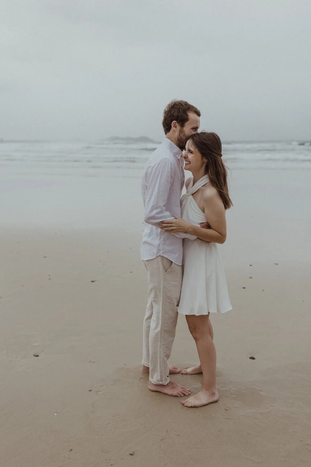 Couple embracing on the beach in the rain, Yoanne and Elisa's rainy elopement at Broken Head, Byron Bay