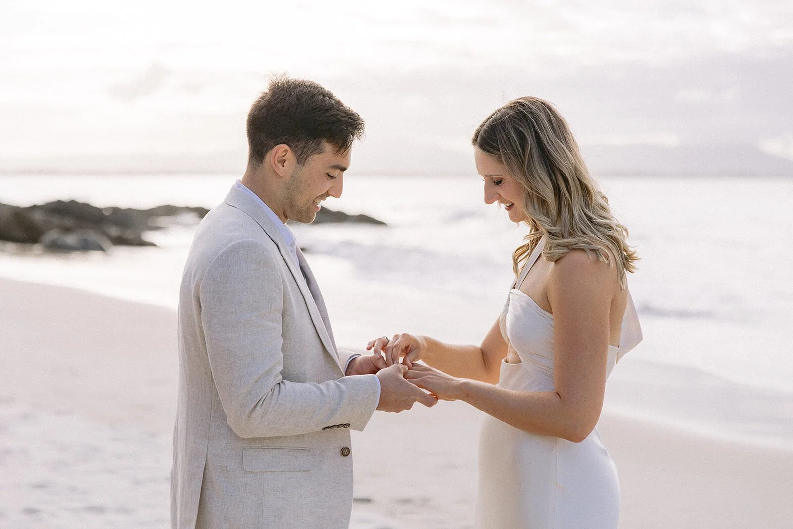 Groom placing the ring on the bride's finger, Abby and James' elopement at Little Wategos Beach, Byron Bay