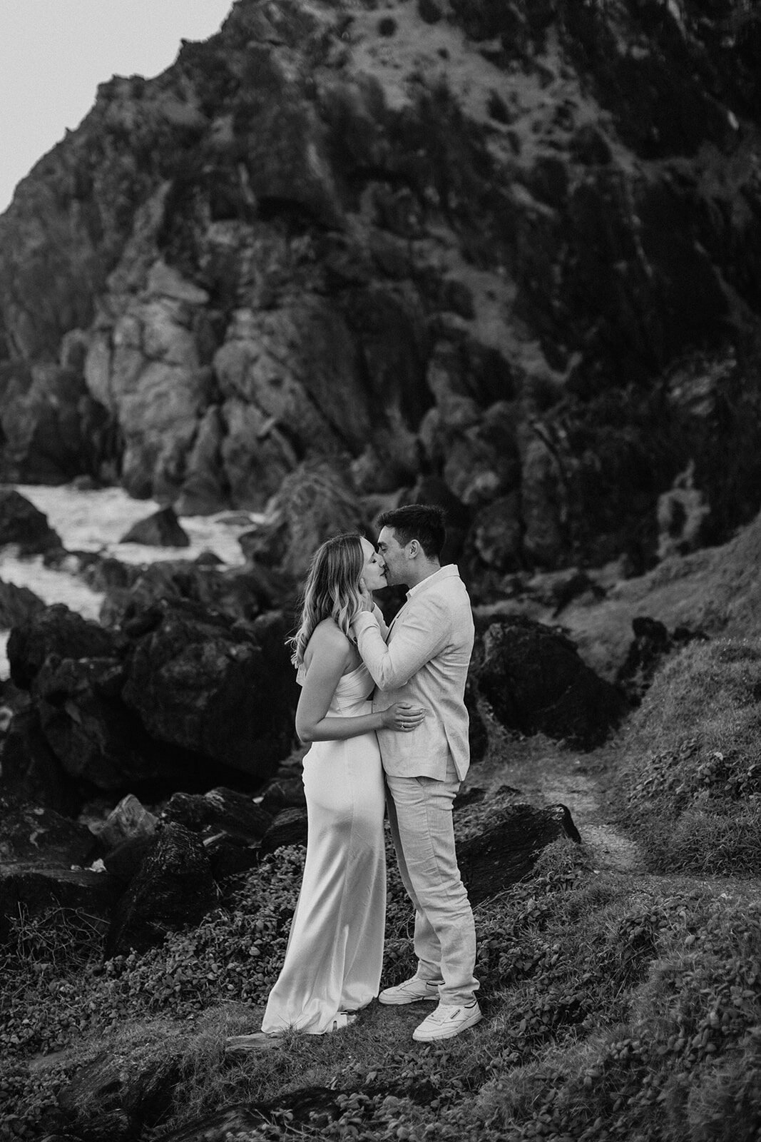 Black and white of the couple kissing among the cliffside rocks, Abby and James' elopement at Little Wategos Beach, Byron Bay