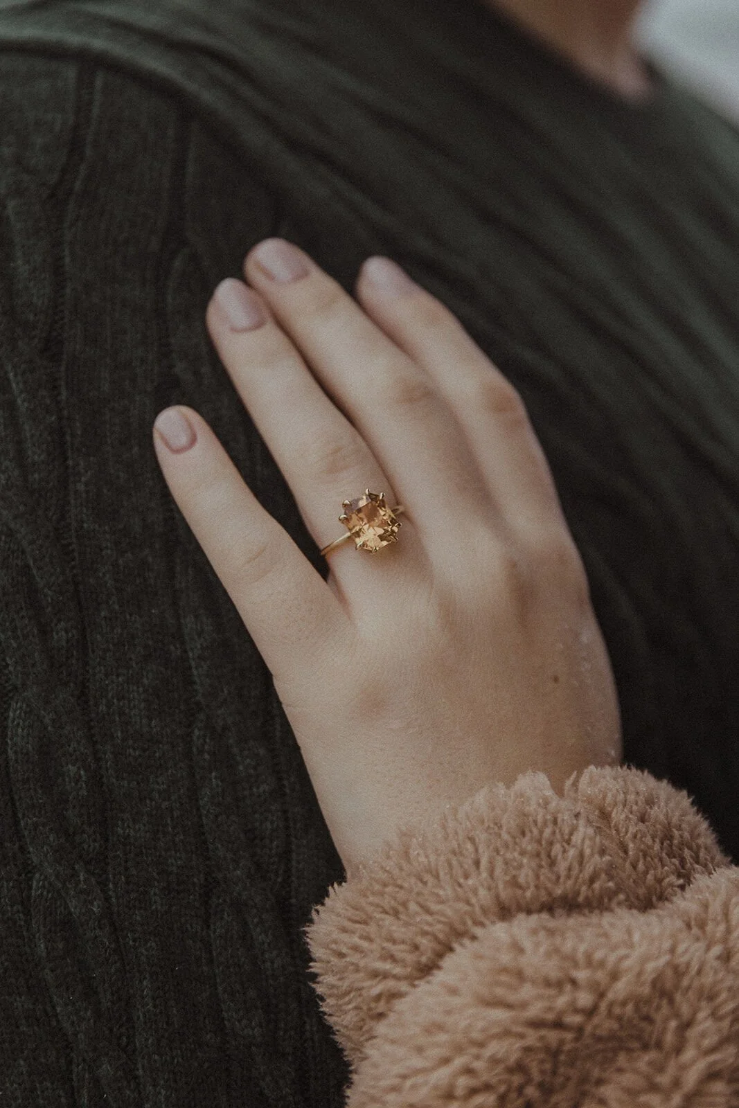 Close up of the gold engagement ring on her hand against his green knit jumper, Raphael and Vany's rainy day marriage proposal at Broken Head Beach, Byron Bay