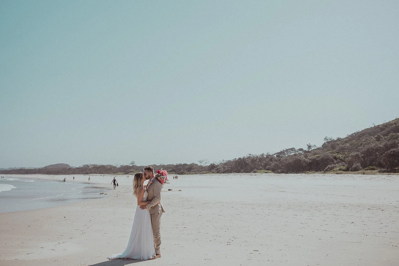 Couple embracing on a wide empty beach, Eliza and Greg's elopement at Broken Head, Byron Bay