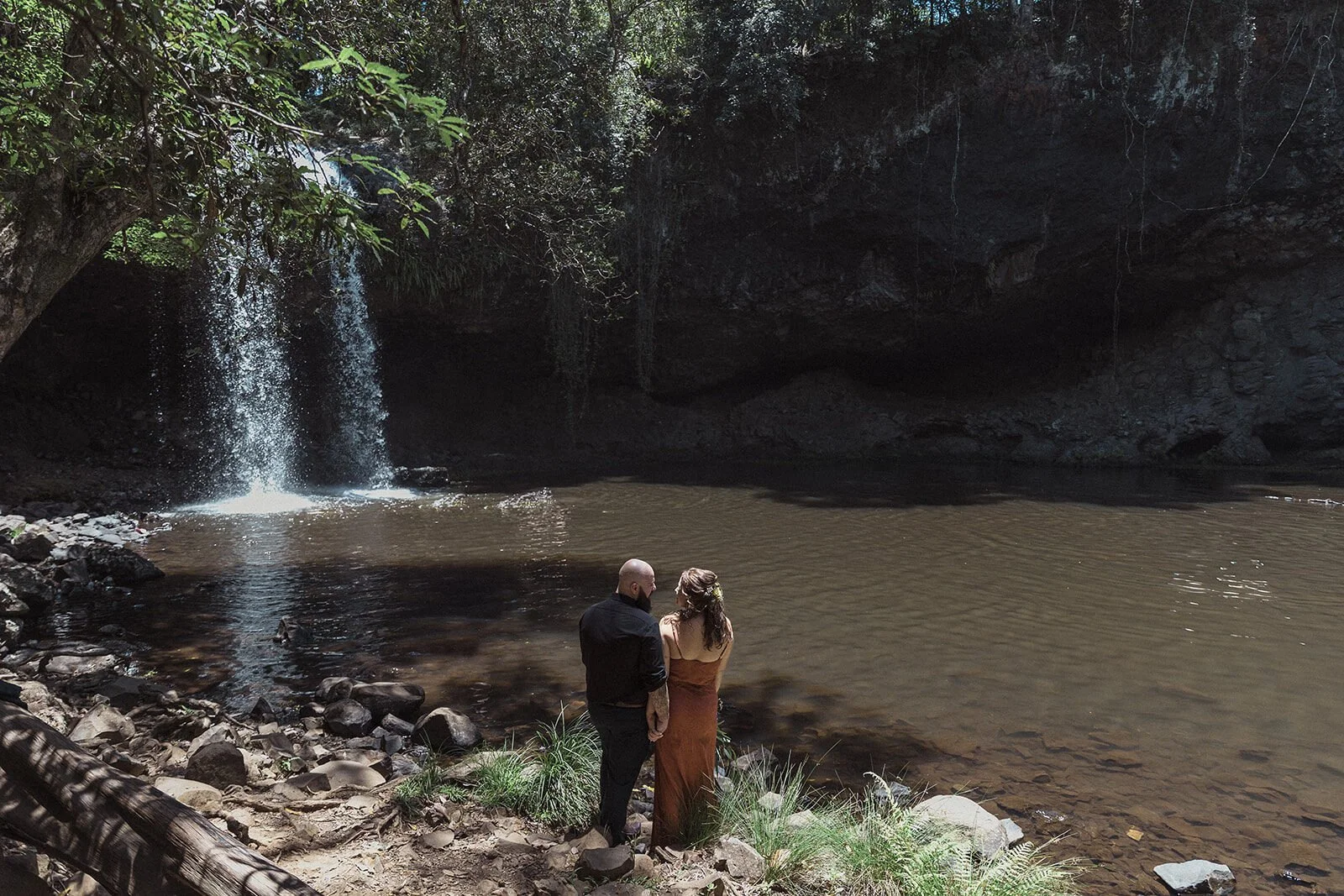 Couple looking at the waterfall from the pool's edge, Sara and Graeme's elopement at Killen Falls, Northern Rivers
