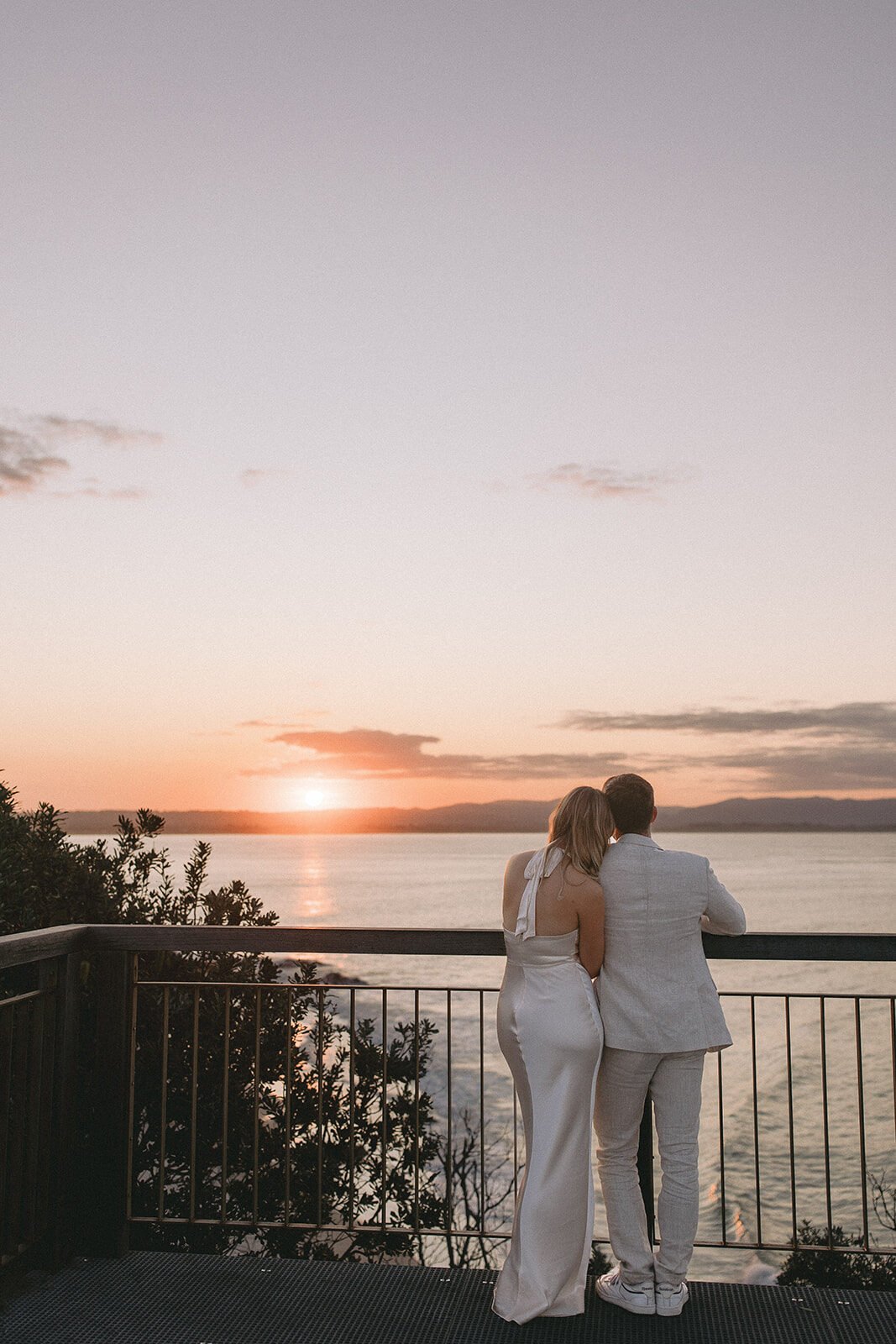 Couple watching the sunset from a lookout railing, Abby and James' elopement at Little Wategos Beach, Byron Bay