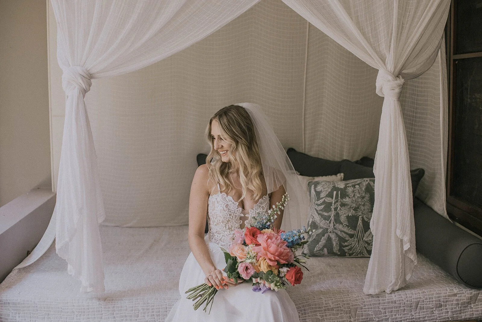 Bride sitting on a daybed with a colourful bouquet, Eliza and Greg's elopement at Broken Head, Byron Bay