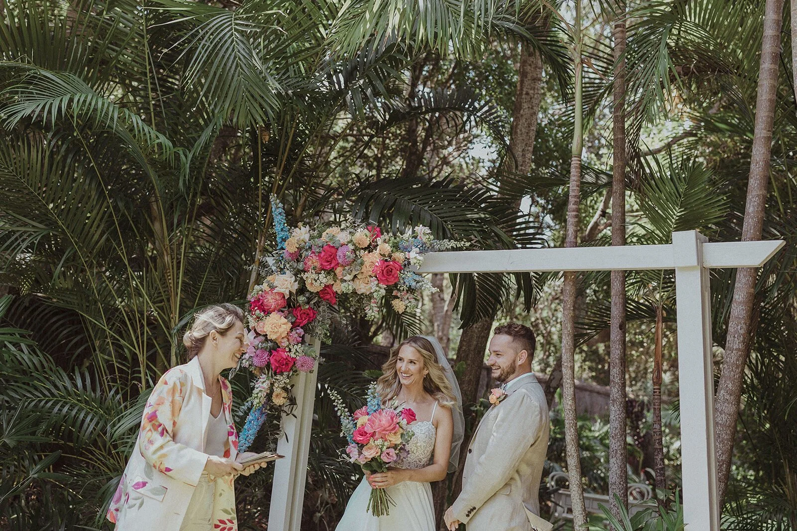 Celebrant marrying the couple beneath the floral arch, Eliza and Greg's elopement at Broken Head, Byron Bay