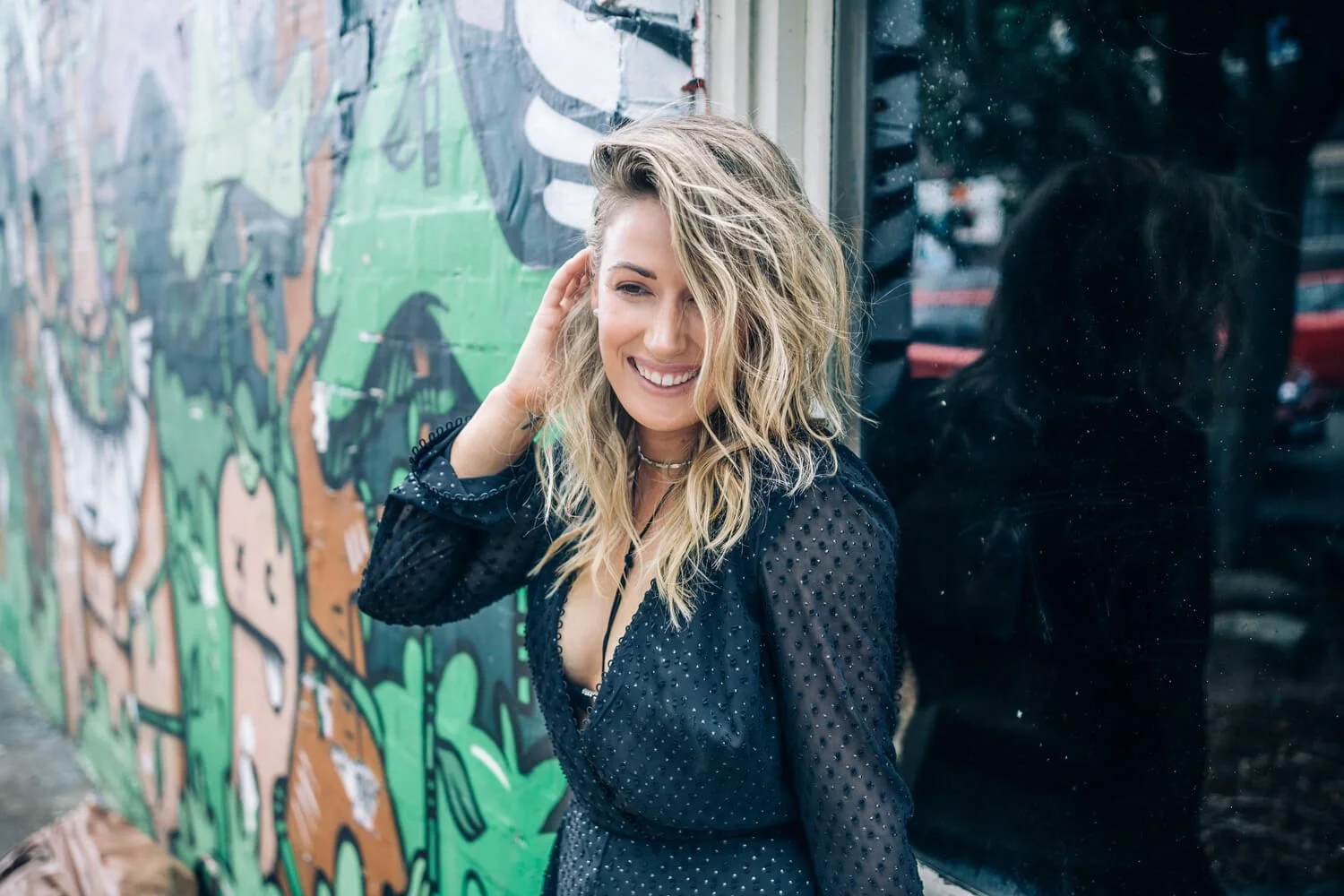 Woman smiling against a street-art mural during a Bondi lifestyle shoot for Ellebeo