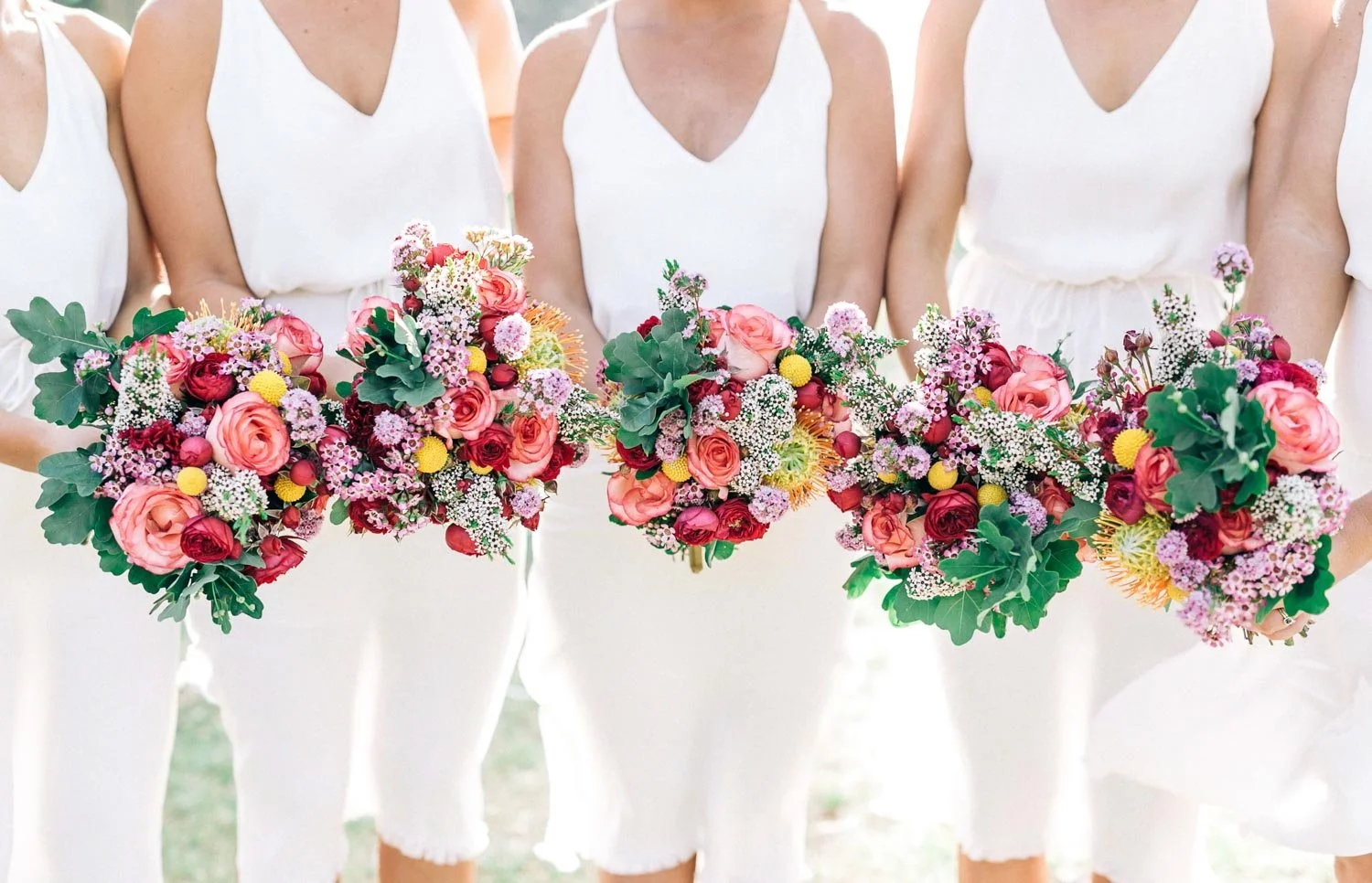 Bridesmaids in white holding bright pink bouquets at a Bilgola Beach wedding