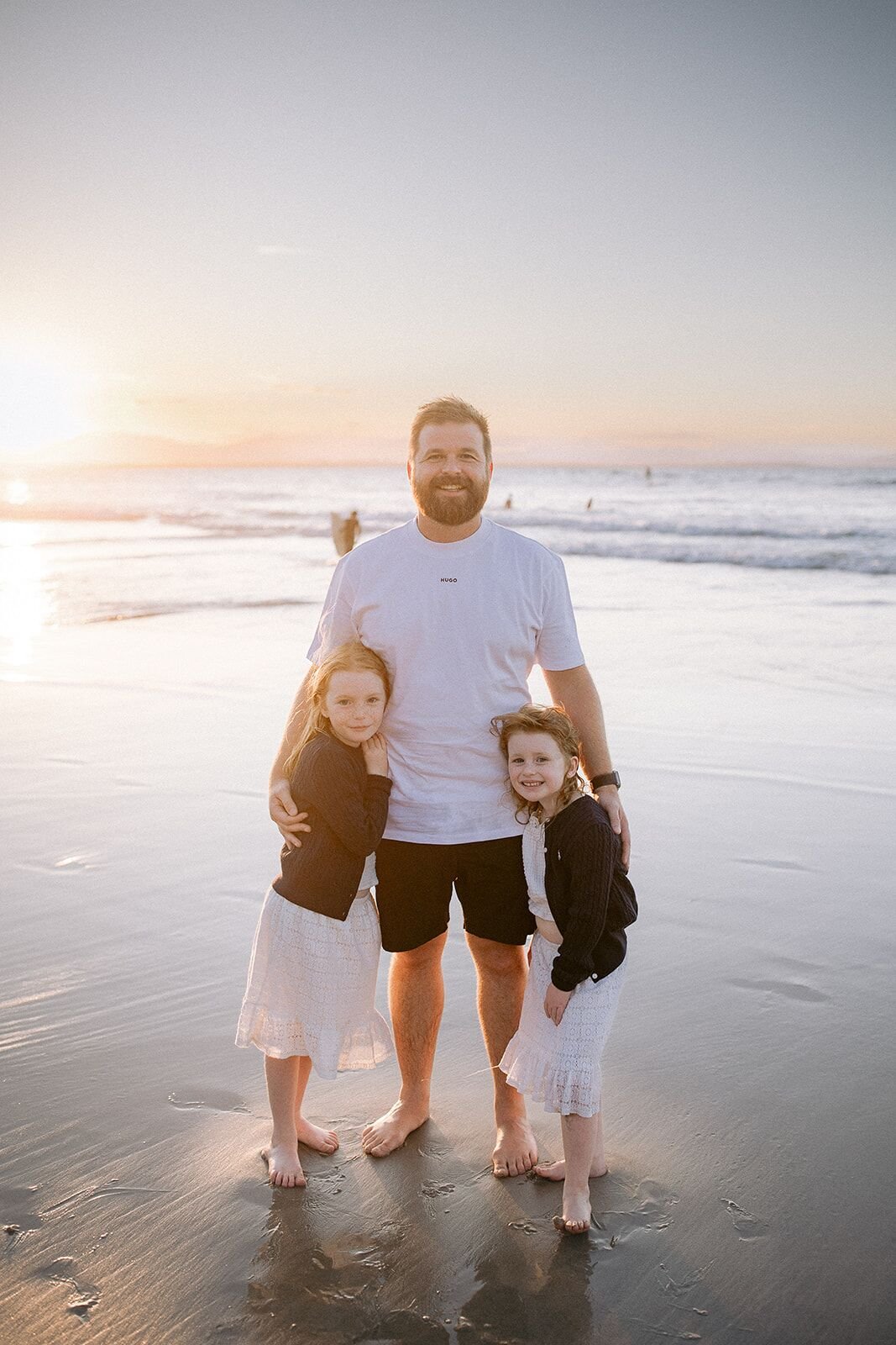 Dad with his two daughters on the wet sand at sunset