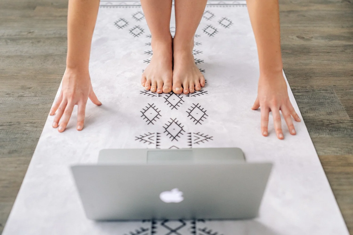 Bare feet on a yoga mat beside an open laptop for an online yoga class shoot