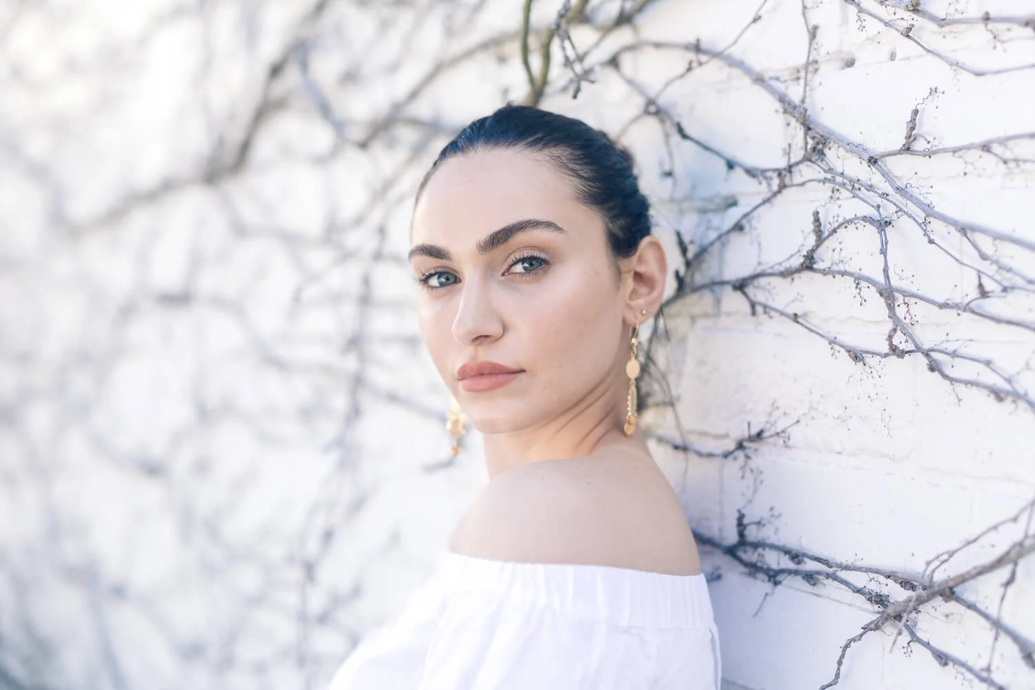 Portrait of a woman in an off-the-shoulder top against a pale backdrop