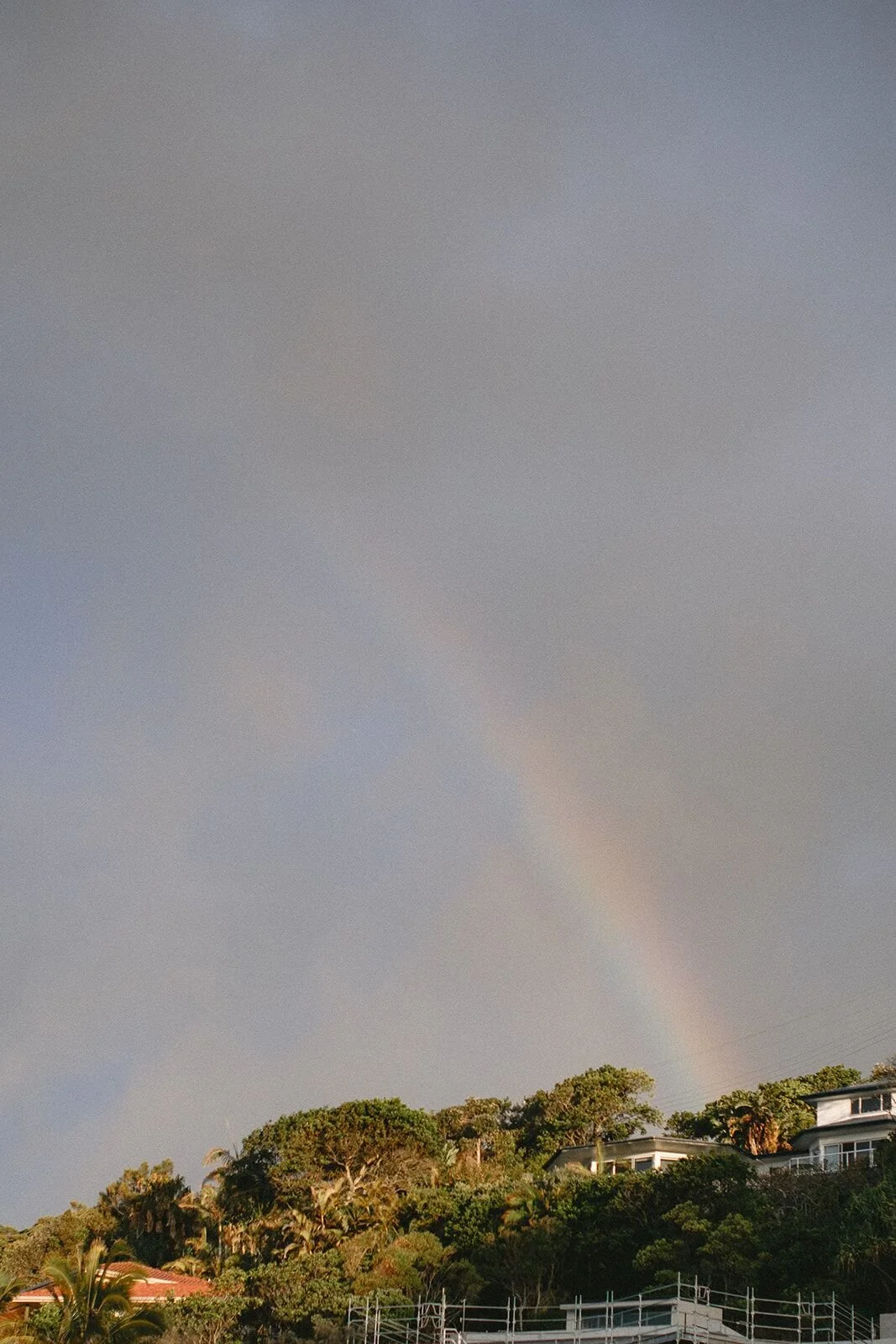Rainbow arching over the headland at Wategos Beach after a storm