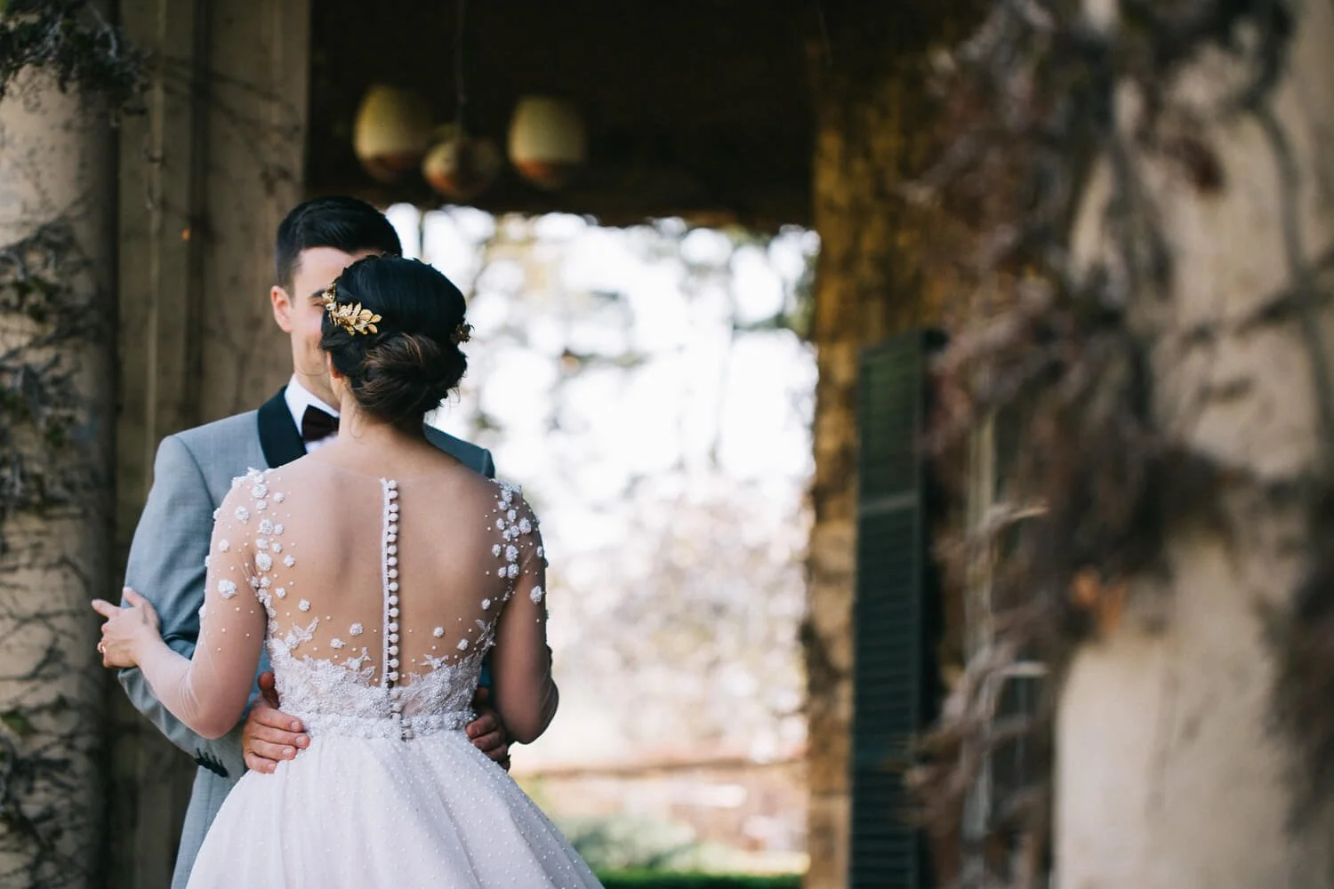Bride and groom embracing beneath a vine-covered stone archway at Bendooley Estate