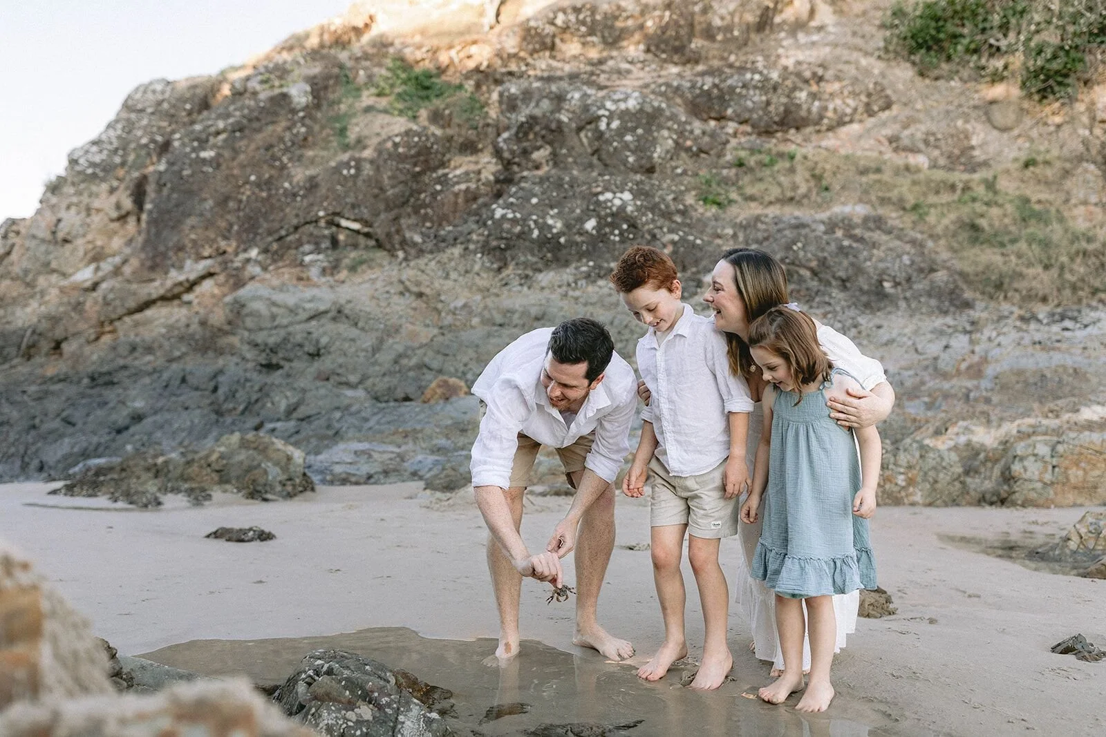 Family of four exploring the rock pools at The Pass, Byron Bay, at sunset