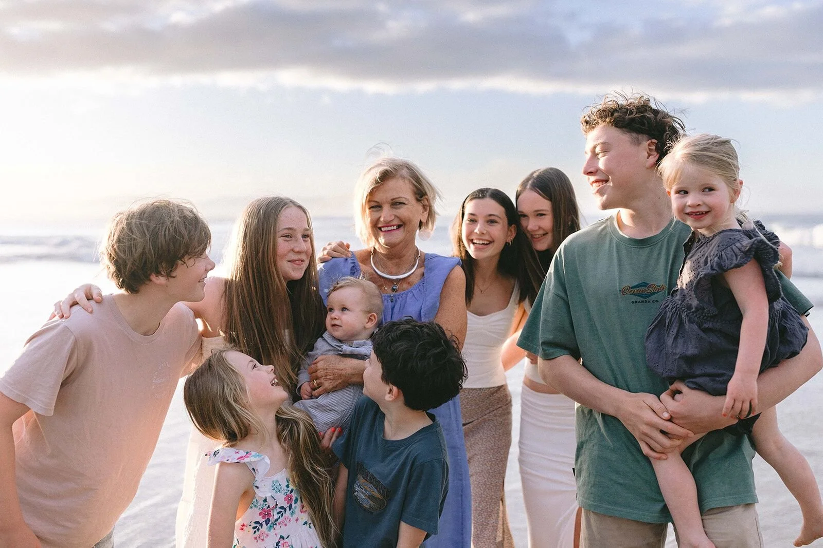 Grandparents, cousins and kids crowded together laughing, a baby cuddled in the middle