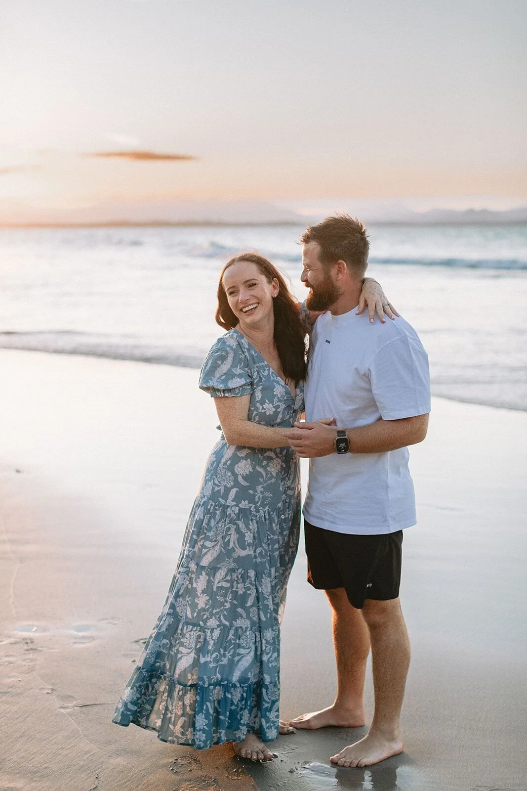 Mum and dad sharing a close moment on the sand at Wategos Beach at sunset