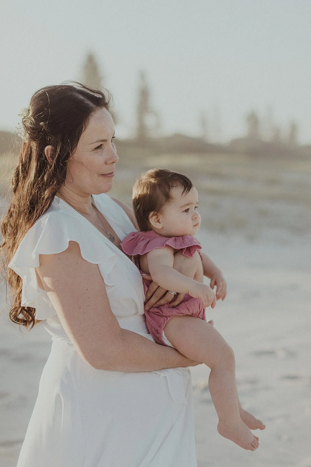 Bride in white holding a baby on the beach, Maritess and Mark's elopement at Lennox Head