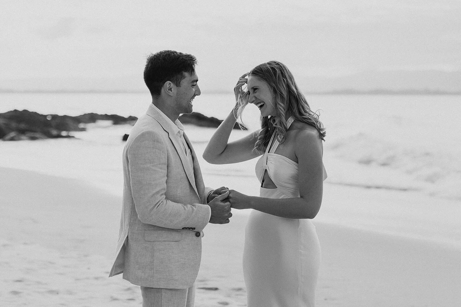 Black and white of the couple laughing together at the water's edge, Abby and James' elopement at Little Wategos Beach, Byron Bay