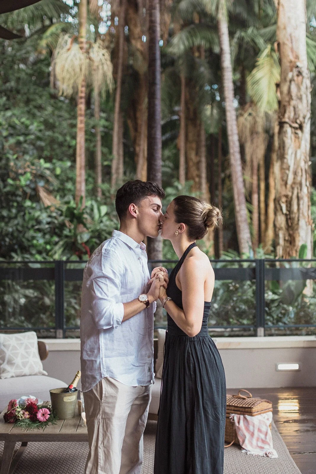 Couple kissing with hands clasped on the deck, Ben and Chloe's marriage proposal in Byron Bay