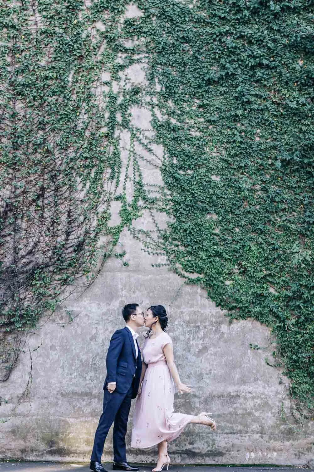 Couple kissing in front of an ivy-covered sandstone wall in The Rocks, Sydney