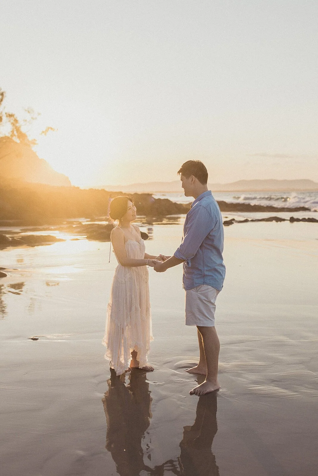 Couple holding hands in the shallow water at sunset, Maggie and William's pre-wedding photos in Byron Bay