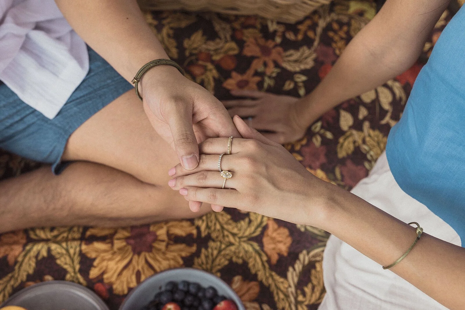 Close up of the couple's hands and the engagement ring on the patterned rug, Darien and Jacqui's picnic marriage proposal at Heartwood Farm, Byron Bay hinterland
