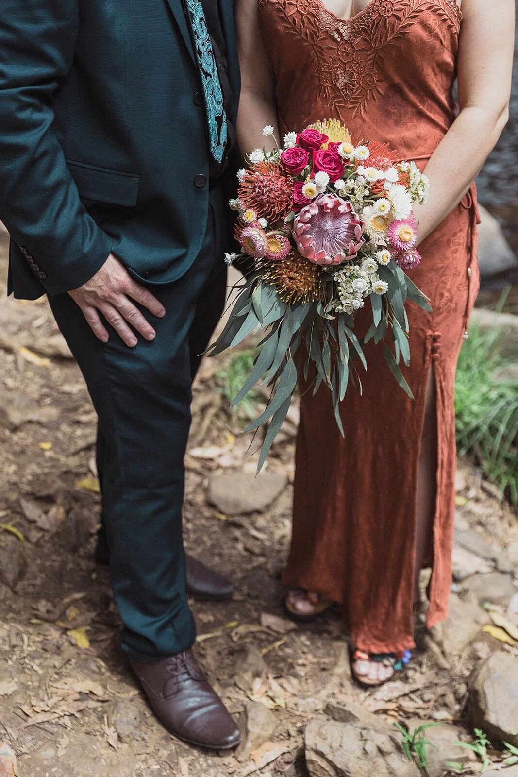 Detail of the bride's bouquet of proteas beside the groom's suit, Sara and Graeme's elopement at Killen Falls, Northern Rivers