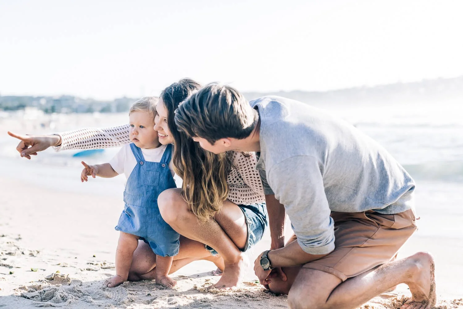 Parents crouching on the sand with their toddler at Bondi Beach