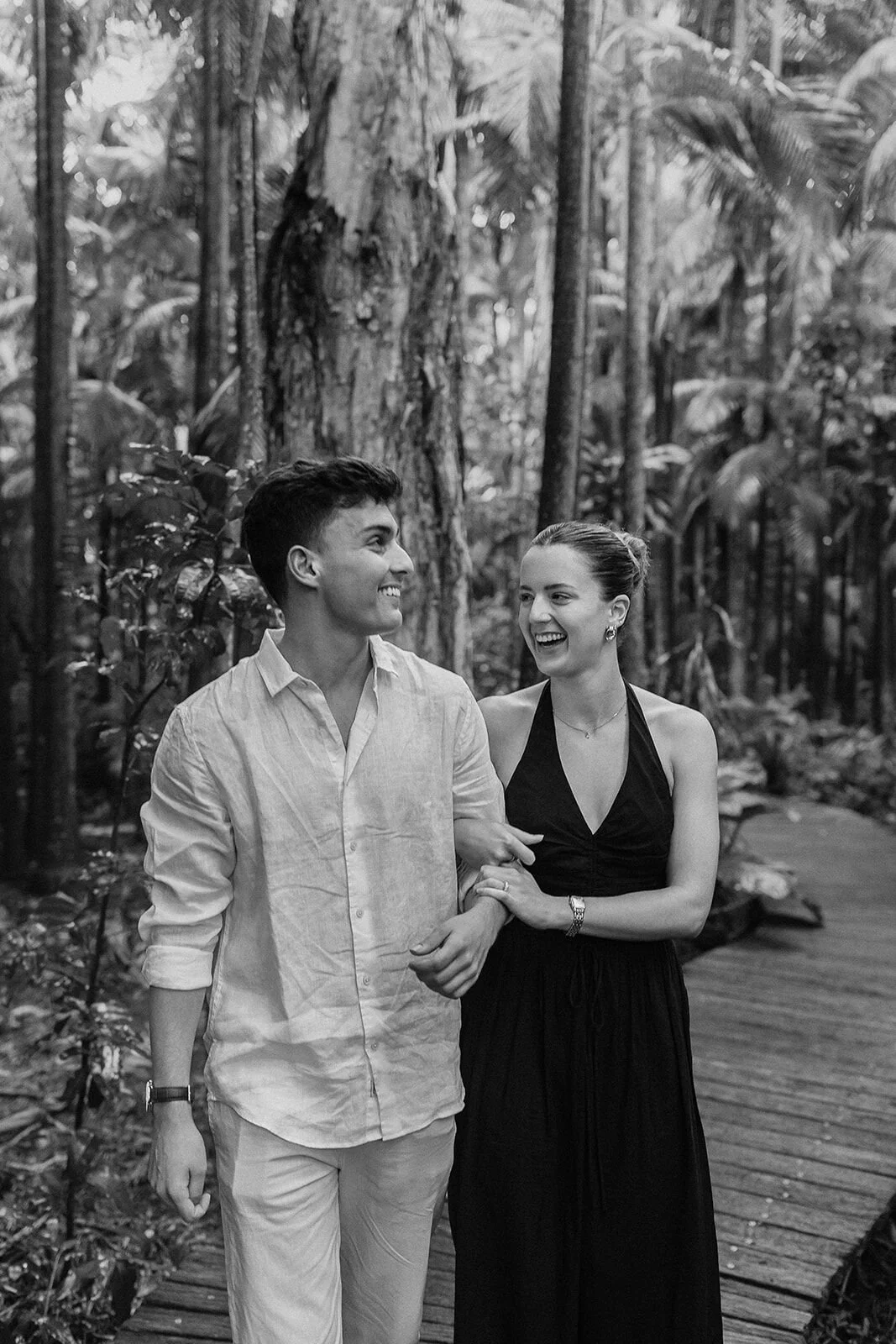Black and white of the couple walking arm in arm on the boardwalk, Ben and Chloe's marriage proposal in Byron Bay