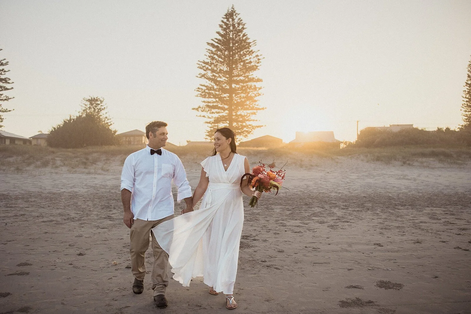 Couple walking toward the camera on the beach at sunset, Maritess and Mark's elopement at Lennox Head