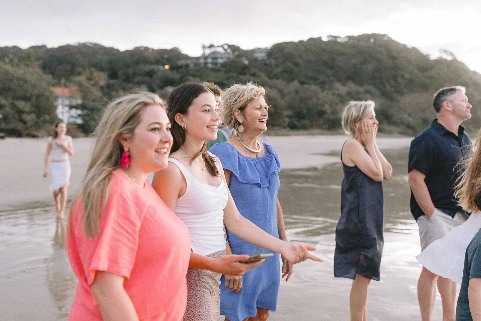 Family members watching the waves together, smiling and pointing out to sea