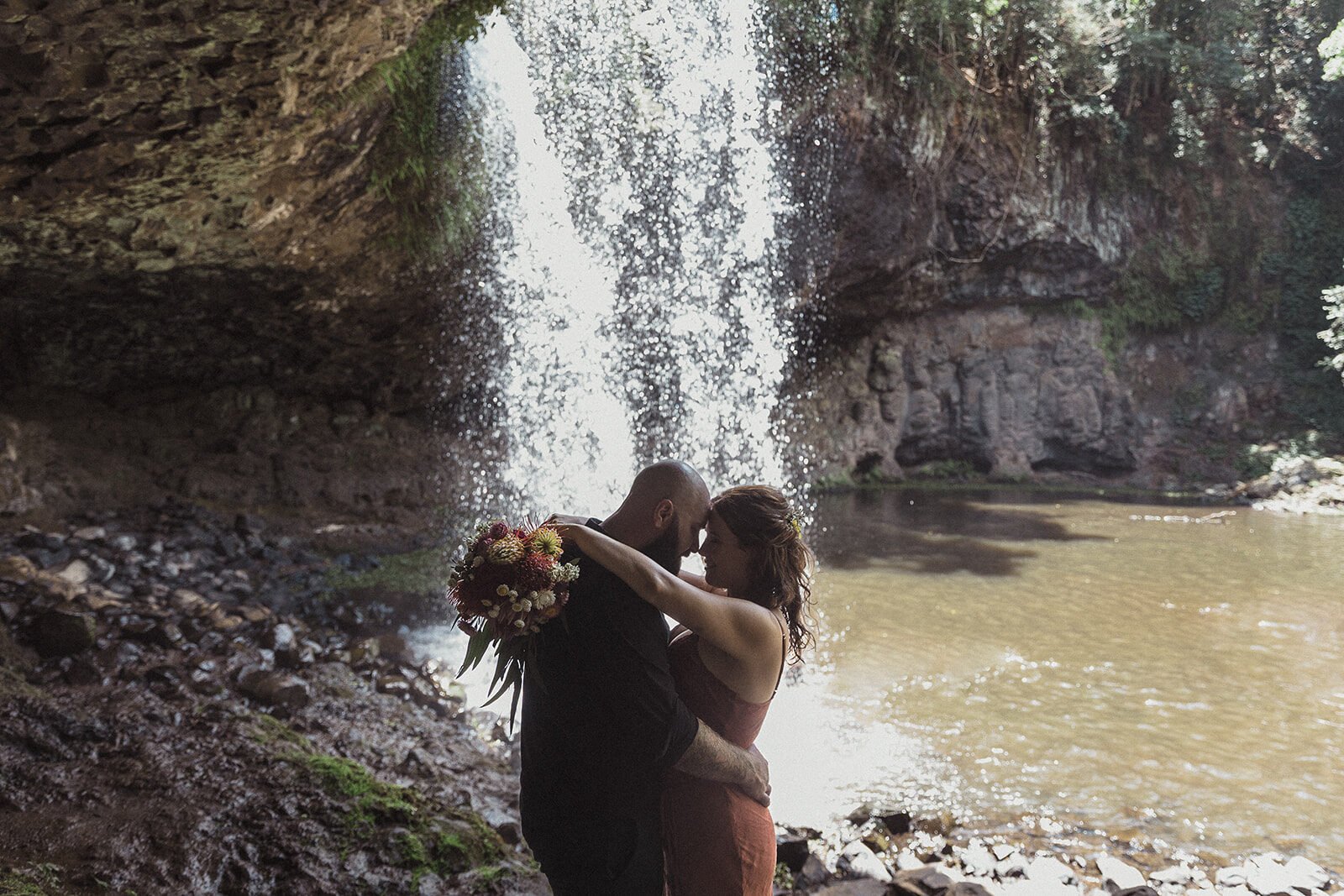 Couple embracing in front of the falling water, Sara and Graeme's elopement at Killen Falls, Northern Rivers