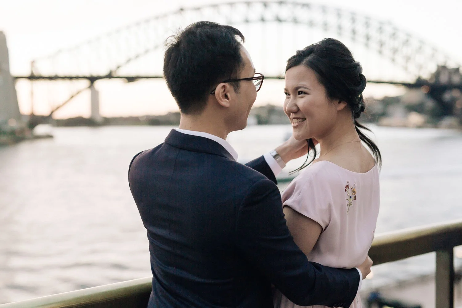 Couple embracing on the harbour foreshore with the Sydney Harbour Bridge behind