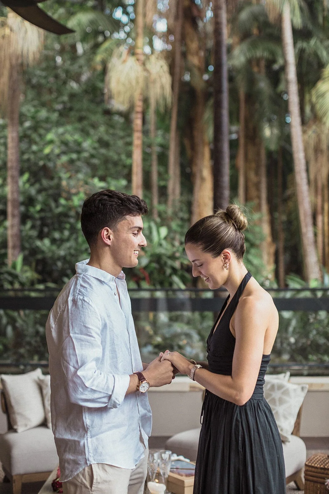Couple holding hands and smiling at the ring in front of the palm forest, Ben and Chloe's marriage proposal in Byron Bay
