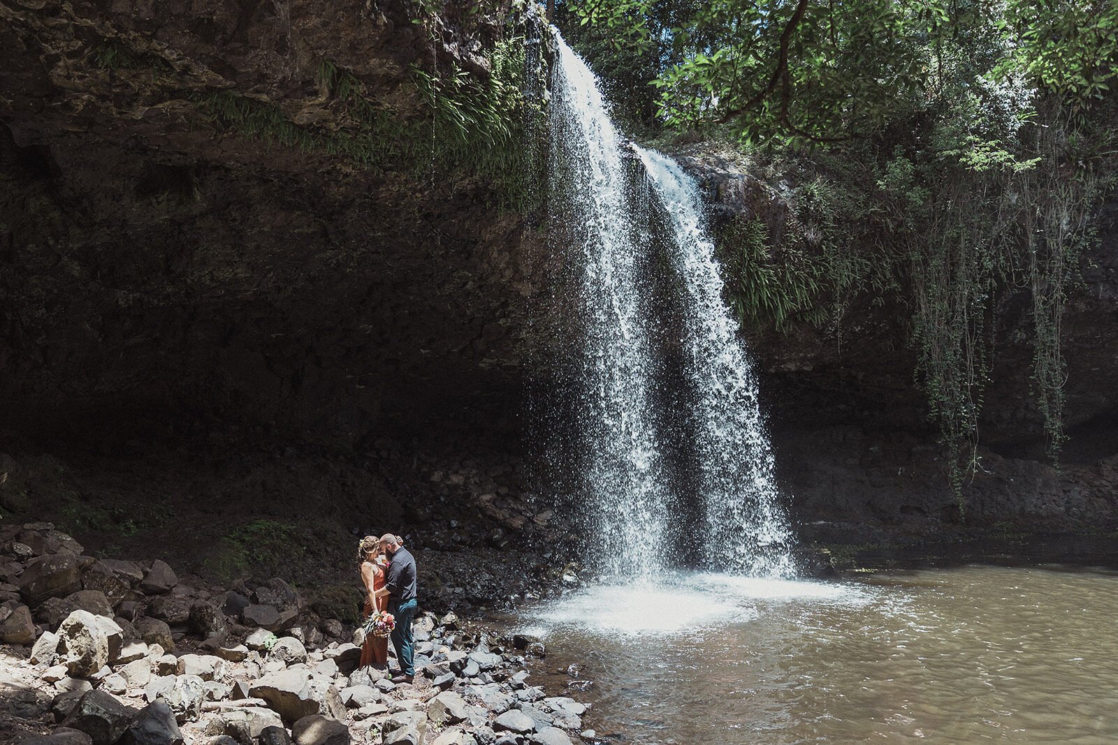 Couple kissing at the base of a tall waterfall, Sara and Graeme's elopement at Killen Falls, Northern Rivers