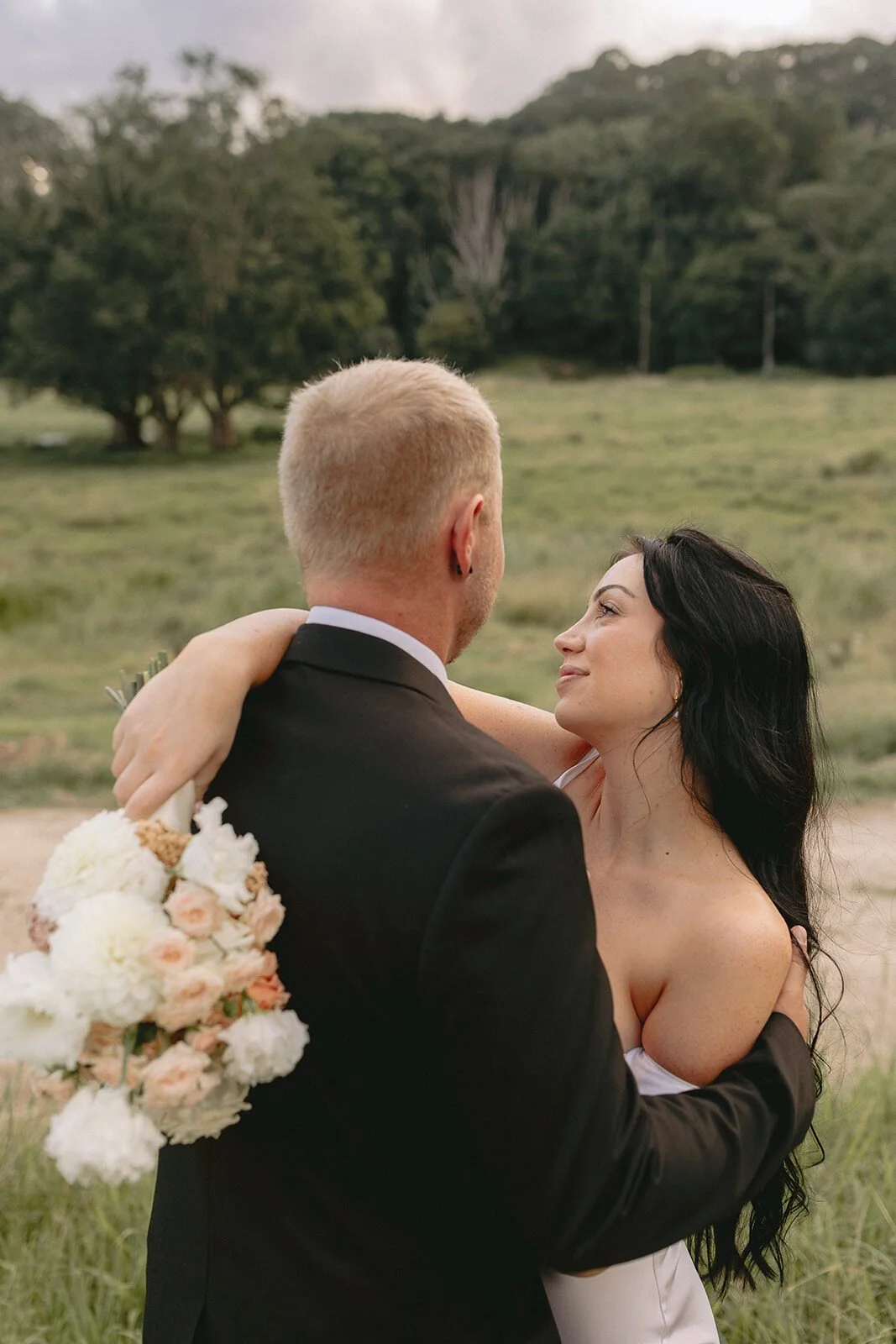 Groom and bride embracing with her bouquet, Kobi and Darren's elopement at Butterfly Lane, Byron Bay hinterland