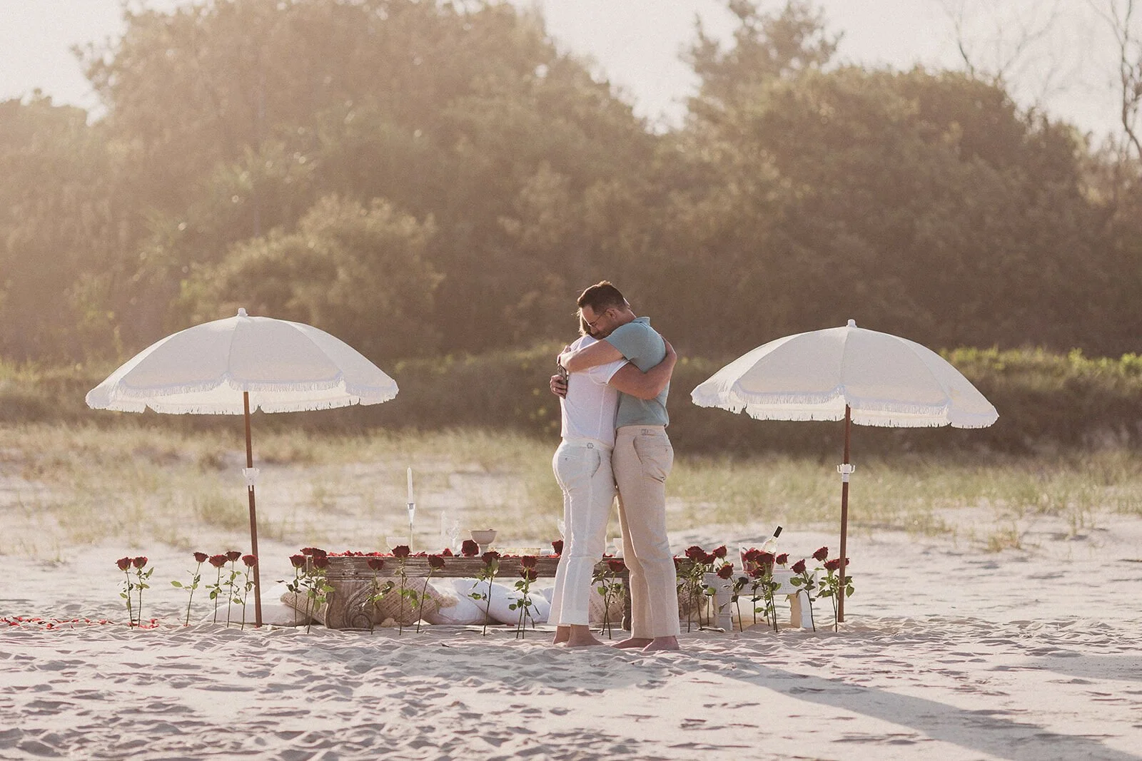 Couple hugging after the proposal in front of the beach picnic set-up, Byron and Luke's marriage proposal at Cabarita Beach, Northern Rivers